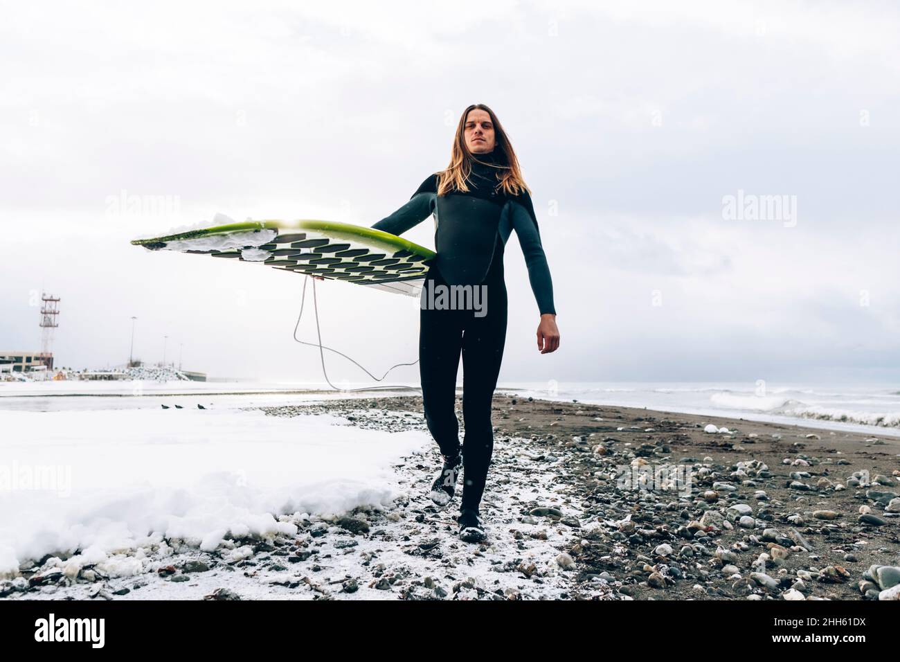 Selbstbewusster Mann mit Surfbrett, der im Urlaub am Strand läuft Stockfoto