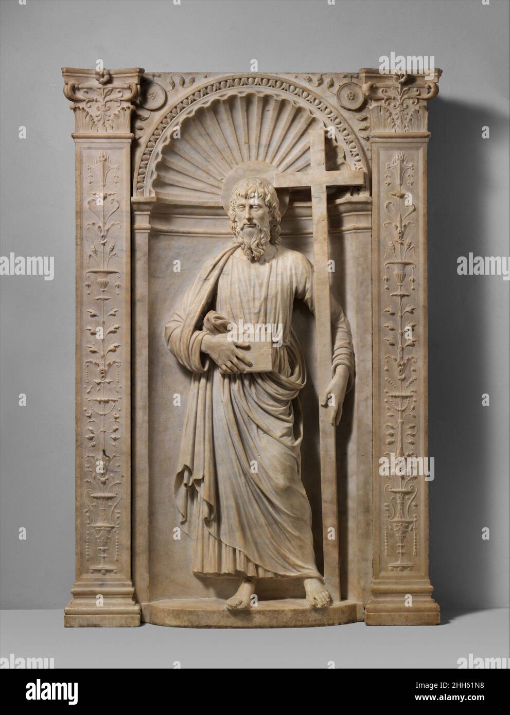 Saint Andrew 1491 Andrea Bregno Italienisch Diese Hochreliefskulptur des Heiligen Andreas, die in einer Nische mit Muscheloberteil steht, befand sich ursprünglich auf einem Altar in Old Saint Peter’s, Rom. Der Plan der Basilika von Tiberio Alfarano aus dem Jahr 1571 zeigt, wo sie sich in der Vorderwand befand.[1] Eine Zeichnung, die vor der Demontage des Altars im Jahr 1606 angefertigt wurde, zeigt über dem Altar drei Heilige in Nischen, die durch fein dekorierte Pilaster getrennt sind: Der heilige Paulus links, der heilige Petrus in der Mitte und der heilige Andreas rechts. In der Zeichnung dreht Andrew seinen Kopf leicht zu Peter und umarmt mit seinem linken Arm das Kreuz o Stockfoto