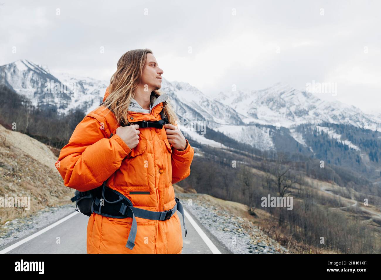 Besinnlicher Mann in oranger Jacke im Winterurlaub Stockfoto