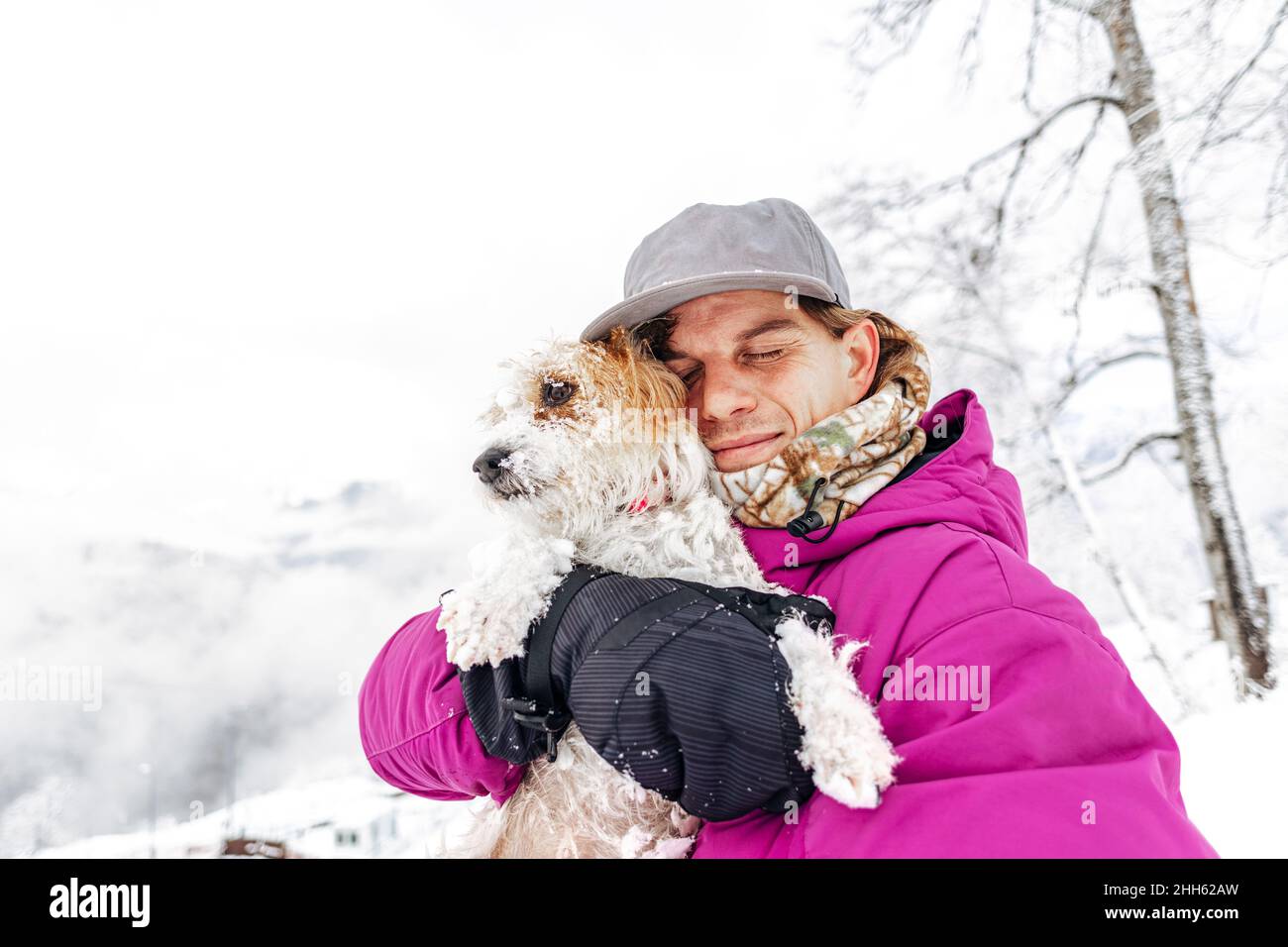 Mann umarmt Jack Russell Terrier im Winterurlaub Stockfoto