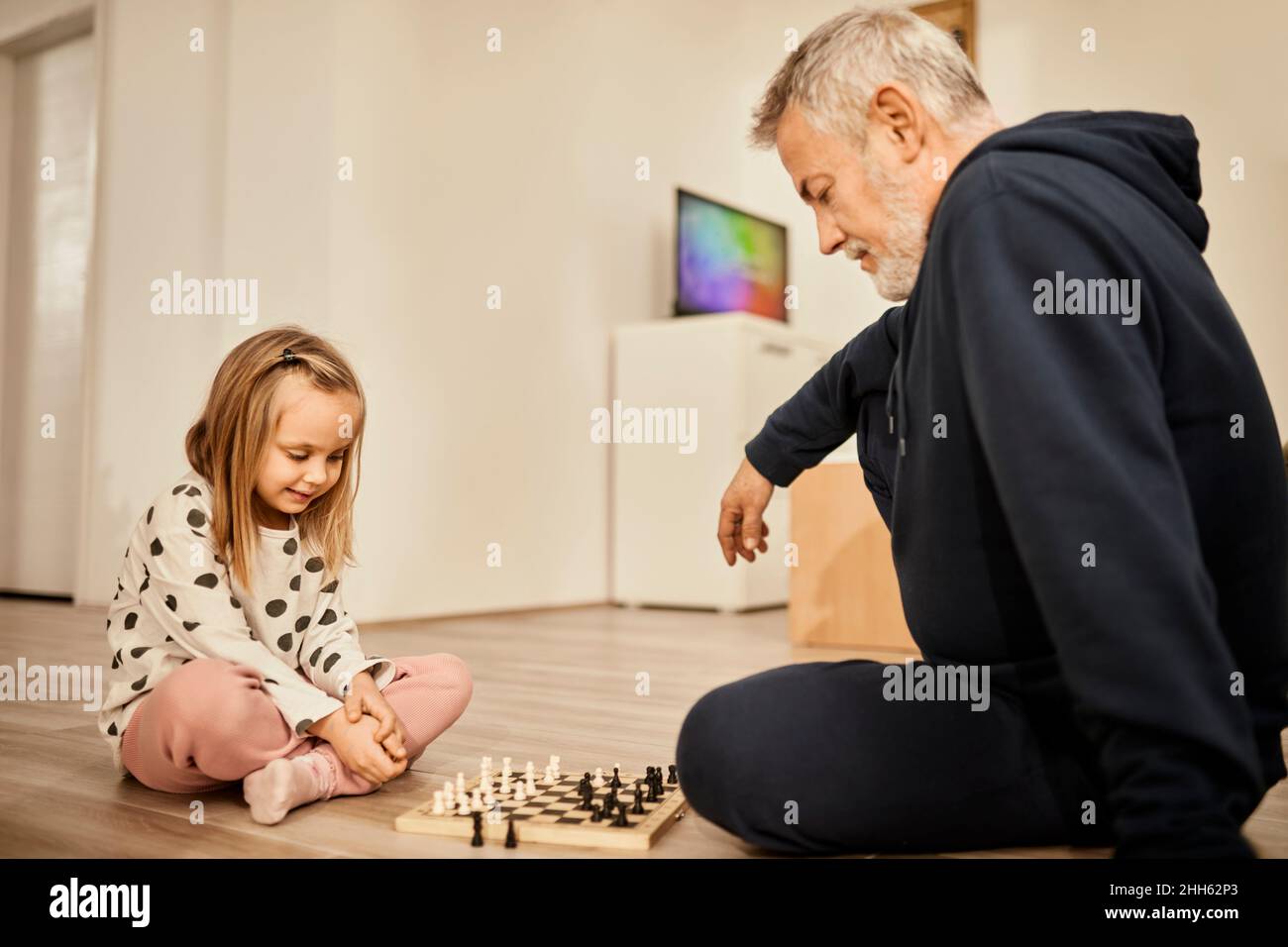 Enkelin und Großvater spielen zu Hause Schach Stockfoto