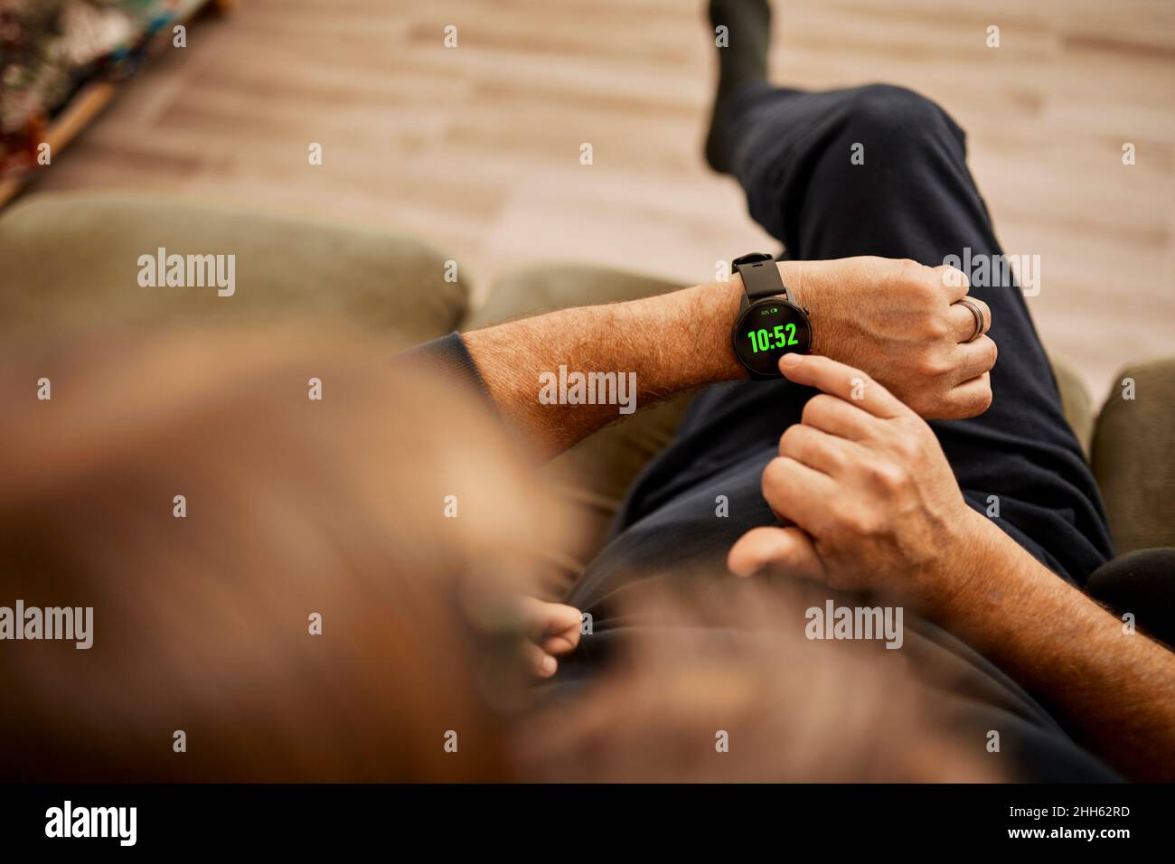 Großvater verwendet eine intelligente Uhr mit Enkelin, die zu Hause sitzt Stockfoto