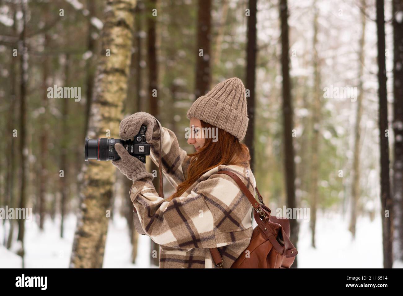 Frau, die im Winterurlaub mit der Kamera im Wald fotografiert Stockfoto