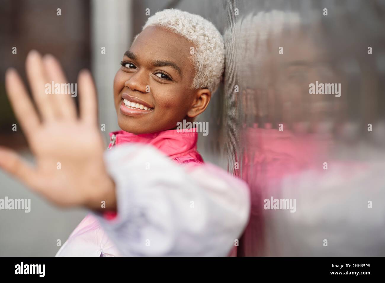 Lächelnde junge Frau gestikuliert Stop-Schild an der Wand gelehnt Stockfoto