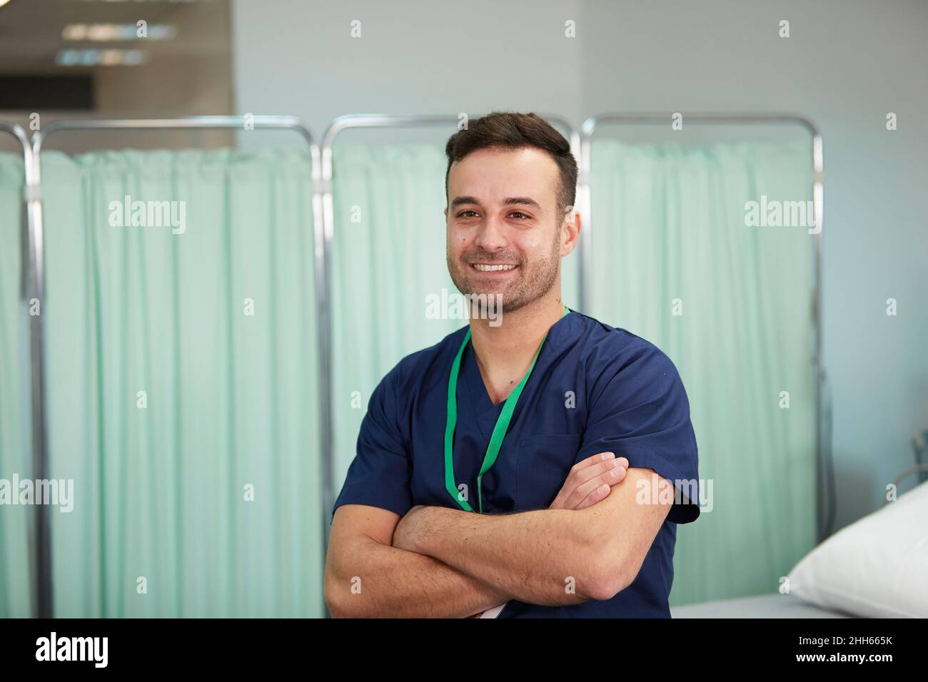 Lächelnde Krankenschwester mit gekreuzten Armen im medizinischen Raum Stockfoto