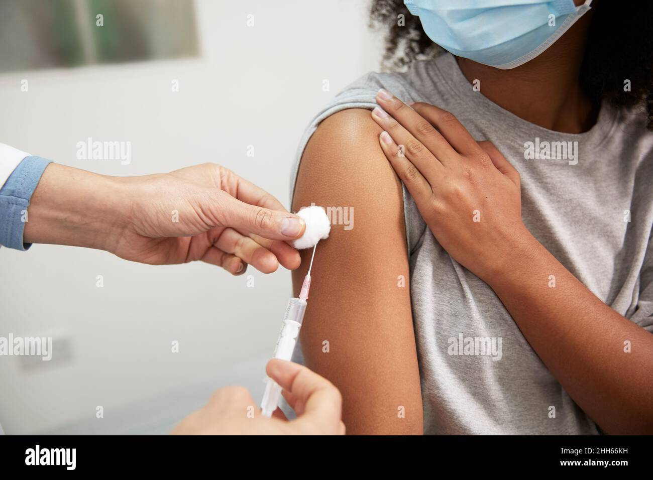 Arzt, der COVID-19-Impfstoff durch eine Spritze in den Arm des Patienten im Krankenhaus einspritzt Stockfoto