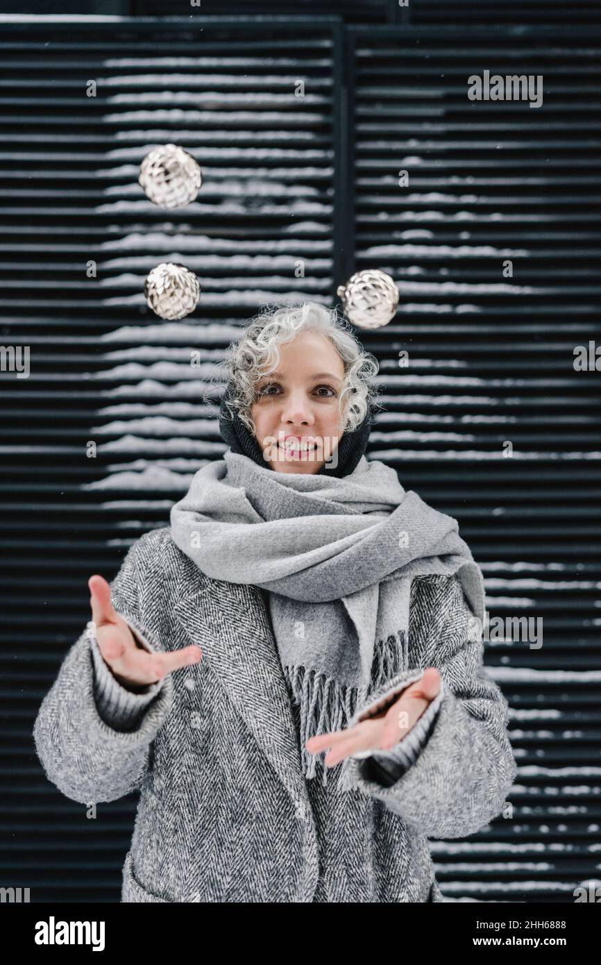 Lächelnde Frau mit grauen Schal jonglieren Kugeln Stockfoto