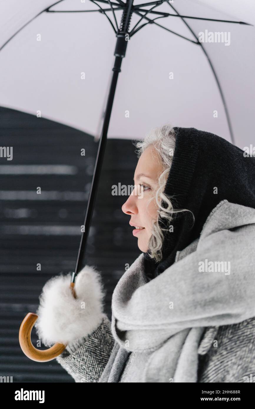 Nachdenkliche Frau mit Regenschirm im Winter Stockfoto