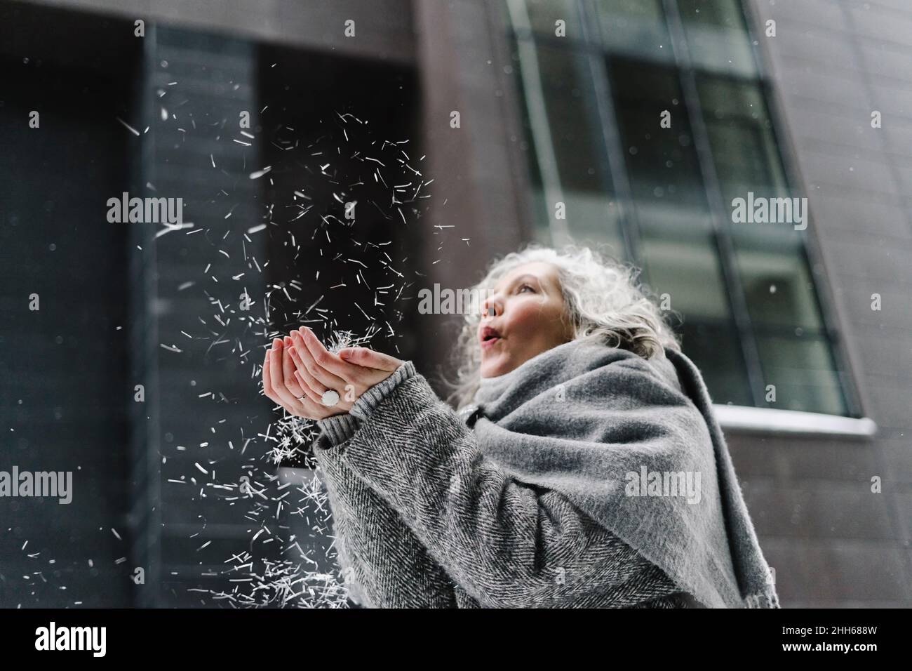 Frau in grauen Schal weht Eiskristalle gewickelt Stockfoto