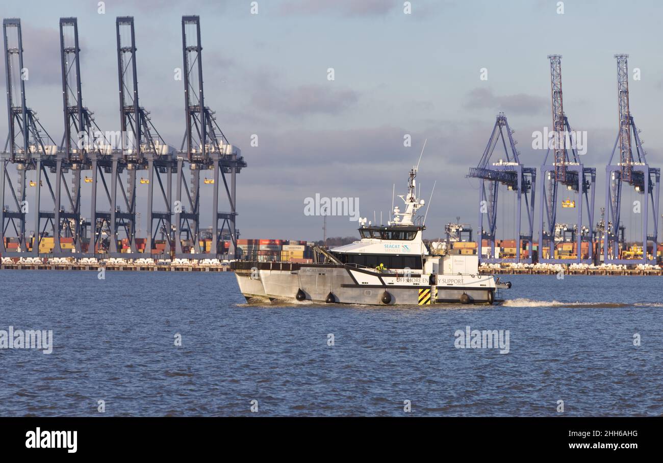 Das Offshore-Energieversorgungs-Schiff Seacat Unschef fährt in Harwich Haven mit dem Hafen Felixstowe im Hintergrund ein. Stockfoto