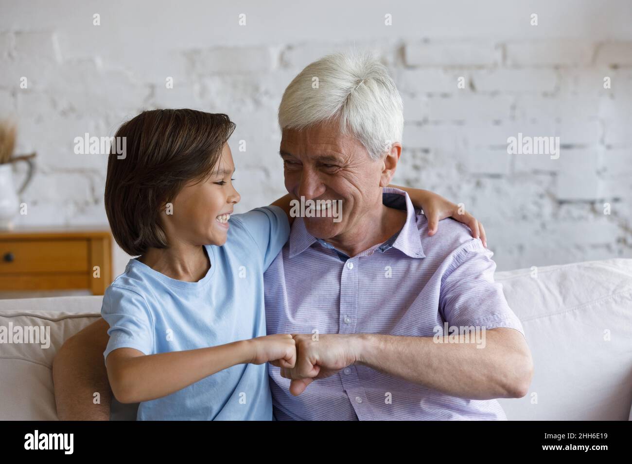 Fröhlicher älterer Großvater und Enkel, der freundliche Faustschlag gab Stockfoto