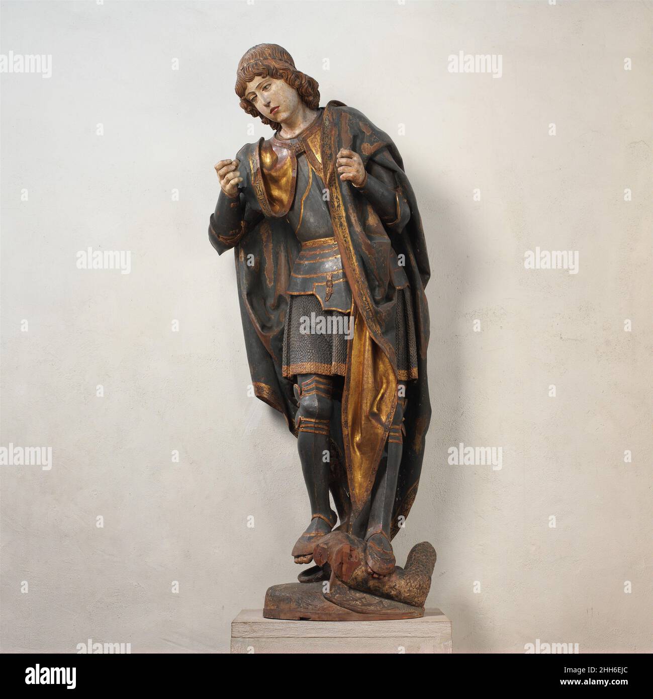 St. Michael Ca. 1530 Spanier der Krieger-Erzengel Michael, bekleidet mit kunstvoll geschnitzten und bemalten Rüstungen, tritt auf einen Drachen, ein Symbol des Teufels. In seiner linken Hand trug er eine Waage, die symbolisch für das jüngste Gericht stand und zu der er irdische Seelen heraufbeschworen hatte. Michaels rechte Hand hielt einst eine Lanze, und seine Flügel sind verloren gegangen. Die sich nach vorne biegende Pose und Verkürzung deuten darauf hin, dass die Figur in einer beträchtlichen Höhe aufgestellt wurde, vielleicht über oder neben dem zentralen Schrein eines großen Retabins. St. Michael 471459 Stockfoto