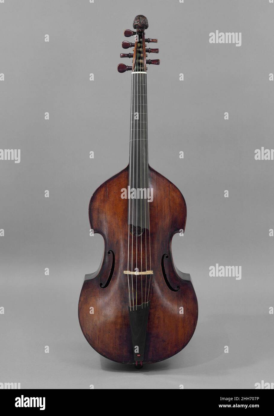 Bass Viol 18th Century möglicherweise von Matthias Humel Deutsch die Familien Gambe und Violine bestehen beide aus Streichinstrumenten mit Sanduhr-Silhouetten, aber die beiden unterscheiden sich in der Anzahl der Saiten (vier für die Violinfamilie, normalerweise sechs für die Gamben), der Stimmung der Saiten, Und Details ihrer Formen (dickere Rippen und schräge Schultern für die Violen, mehrere Formen von Schalllöchern für Violen gegen S-förmige Schalllöcher für Violen, flache Rücken für Violen gegen gewölbte Rücken für Violen, sowie weit mehr Vielfalt an Konturen für Violen als Violen). Violen haben Bünde auf ihren Griffbrettern, Stockfoto