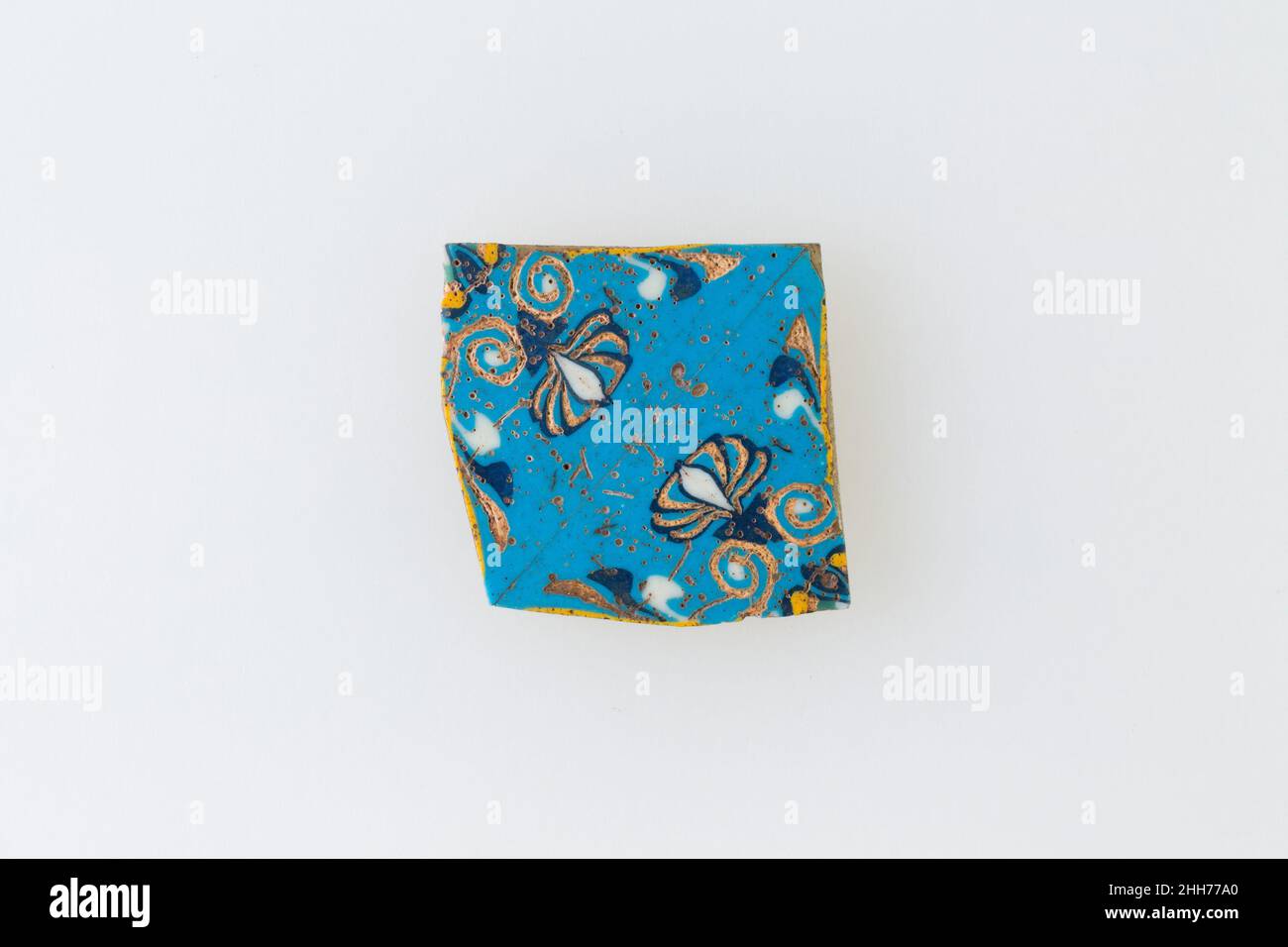 Inlay, palmette 100 v. Chr.–100 n. Chr. Ptolemäische Periode–Römische Zeit Eine Mosaikglastechnik ermöglichte die Erstellung von Vielfachen eines Bildes: Eine figürliche oder gestalterische Komposition wurde durch Bündelung von farbigen Glasstöcken hergestellt, die dann zu einem langen Balken herausgezogen wurden. Die Stange wurde dann im rechten Winkel geschnitten, wahrscheinlich durch Aufschlagen der Stange mit geeigneten Werkzeugen, um kleine Inlay-Fliesen zu produzieren. Die Fliese würde dann geglättet und auf dem Gesicht poliert, das nach außen erscheinen soll. Inlay, Palmette. 100 V. CHR.–100 N. CHR. Glas. Ptolemäische Periode–Römische Periode. Aus Ägypten Stockfoto