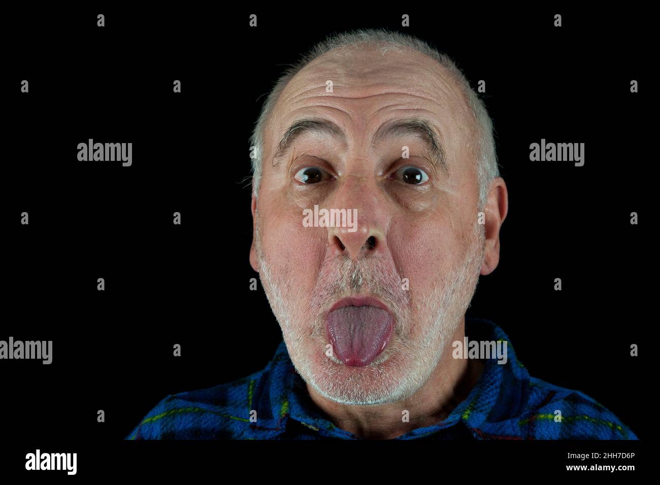 Ein alter Mann streckt seine Zunge gegen den Fotografen aus. Stockfoto