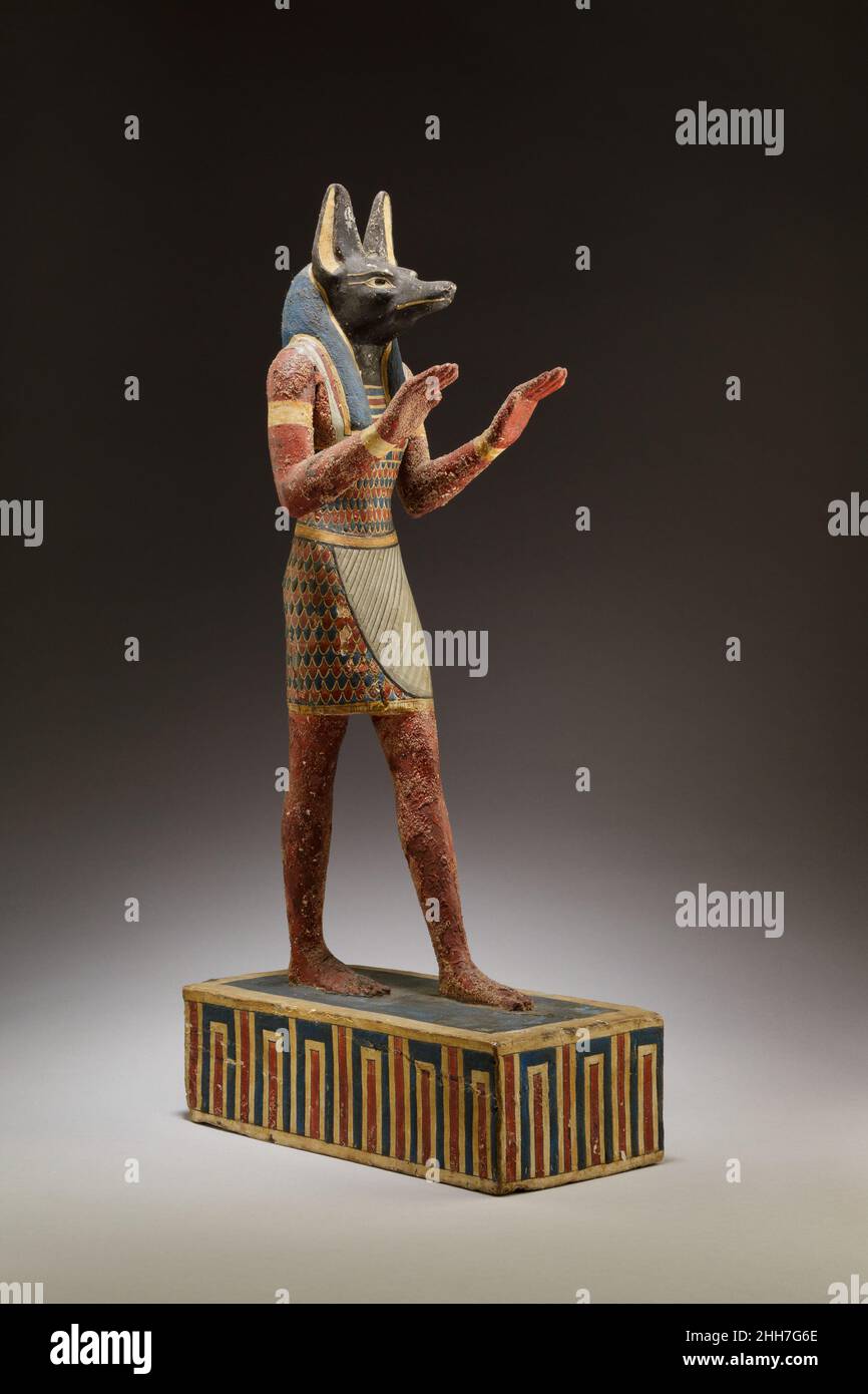 Statuette von Anubis 332–30 v. Chr. Ptolemäische Periode der gott der Mumifizierung Anubis wird hier als Mensch mit Schakalkopf und langer Perücke dargestellt. Er trägt Schmuck und ein Kleidungsstück mit einem aufwendigen Federmuster. Anubis wird wahrscheinlich dargestellt, um den Verstorbenen im Jenseits zu begrüßen und ihn zu beschützen. Die Statuette ist exquisit geschnitzt und bemalt (beachten Sie die gemalte Faltung des Kilts). Statuette von Anubis. 332–30 V. CHR. Verputztes und lackiertes Holz. Ptolemäische Periode. Aus Ägypten Stockfoto