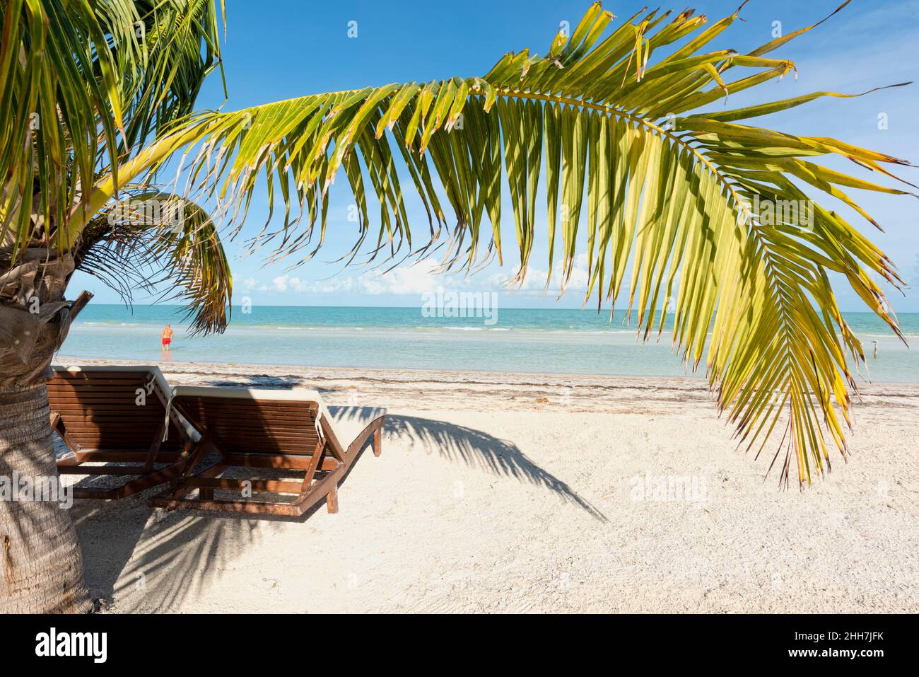 Strandliegen und tropische Palmen, ein Tourist am Meer - Reise- und Urlaubskonzept. Holbox Island Mexiko Stockfoto