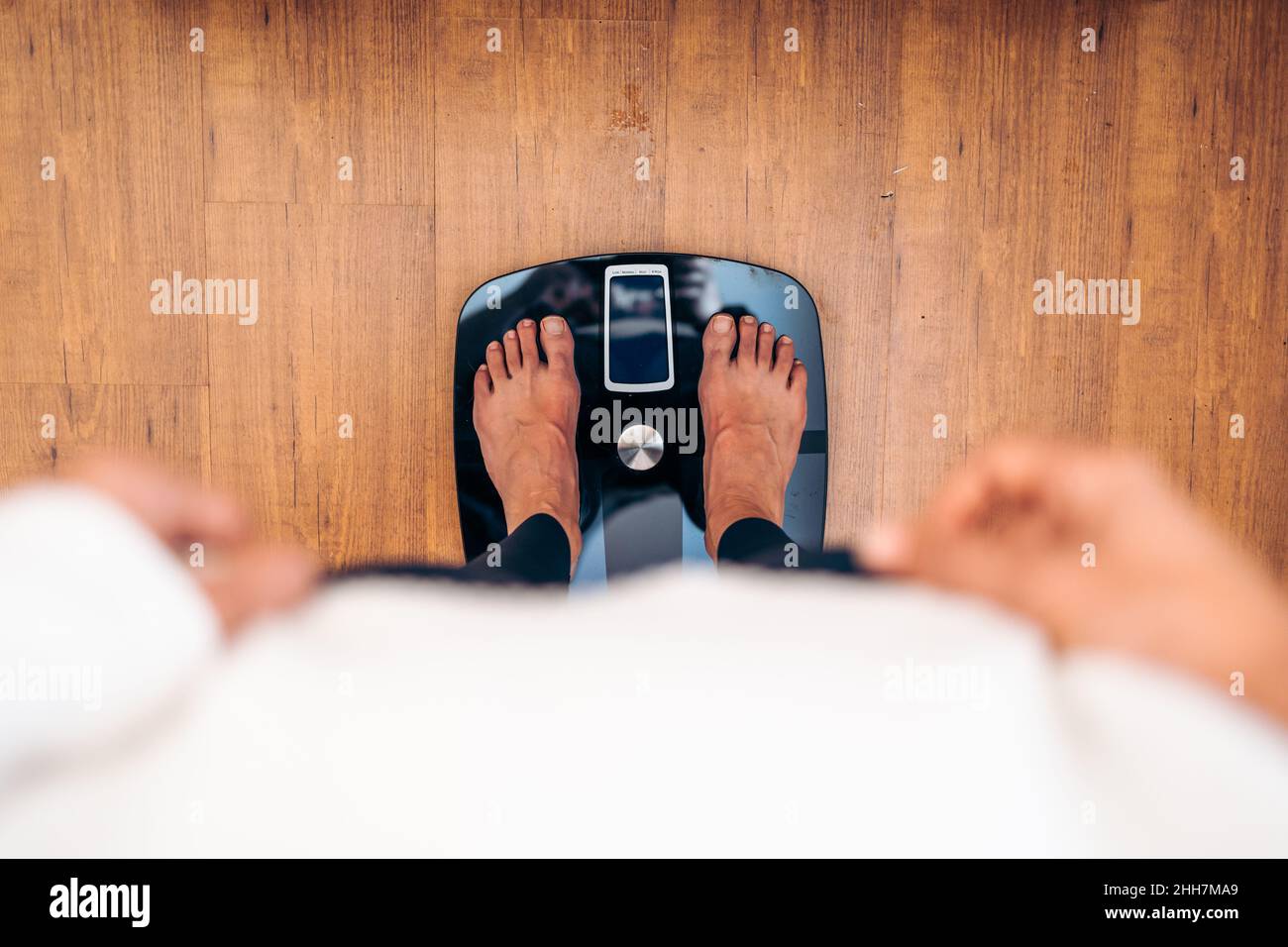 Frau, die sich auf einer Badezimmerwaage wägt. Diät Probleme Konzept Stockfoto
