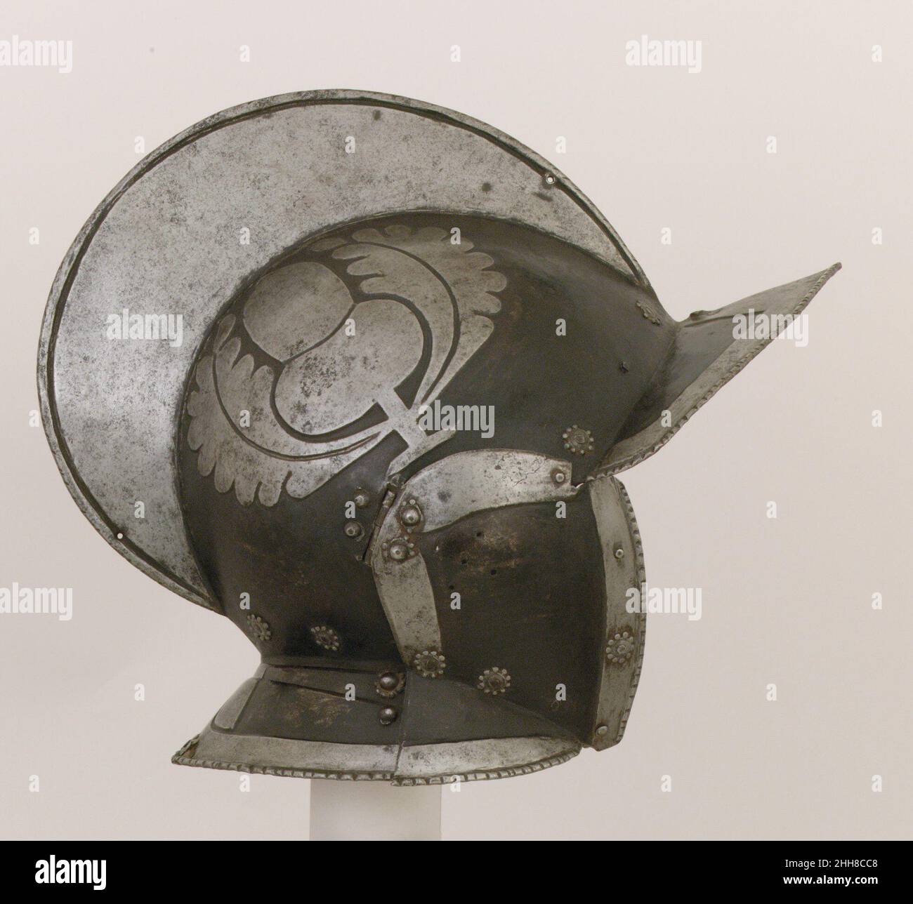 Burgonet für die Wache der Grafen Khevenhüller zu Aichelberg ca. 1580 Deutsch die Eichel- und Eichenblätter, die an den Seiten der Schale geprägt sind, sind Embleme der österreichischen Adelsfamilie Khevenhüller zu Aichelberg (Aichel steht für Eichel). Im Schloss der Familie Hochosterwitz, bei Klagenfürt, ist eine Reihe von „schwarz-weißen“ Rüstungen mit ähnlich verzierten Burgonetten oder Morionen erhalten. Im österreichischen Bundesland Kärnten.für den deutschen Infane wurden zahlreiche standardisierte Rüstungen gefertigt, die mit erhabenen und hell polierten Bändern verziert sind, die durch die schwarz lackierten Untergründe ausgelöst wurden Stockfoto