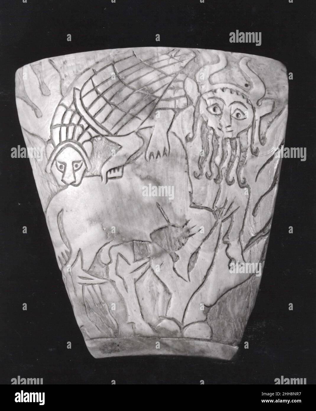 Inlay: Kampf zwischen einem menschenköpfigen Stier und einem löwenköpfigen Adler ca. 2600–2500 v. Chr. Sumerian Diese Tafel wurde aus einem Muschelstück geschnitzt und ist mit dem Bild eines menschköpfigen Stiers versehen, der von einem löwenköpfigen Adler vor einem Hintergrund der Vegetation angegriffen wird. Beide Kreaturen werden mit Körpern in der Profilansicht und Kopf frontal orientiert dargestellt und blicken direkt auf den Betrachter. Der Körper des menschköpfigen Bullen ist stämmiges und kraftvolles, und der lange Schwanz bürstet den Boden. Sein Gesicht, mit großen Augen, deren Pupillen durch Bohren betont wurden, wird von einem Bart langer Einzelschlösser beringt, die jeweils in enden Stockfoto