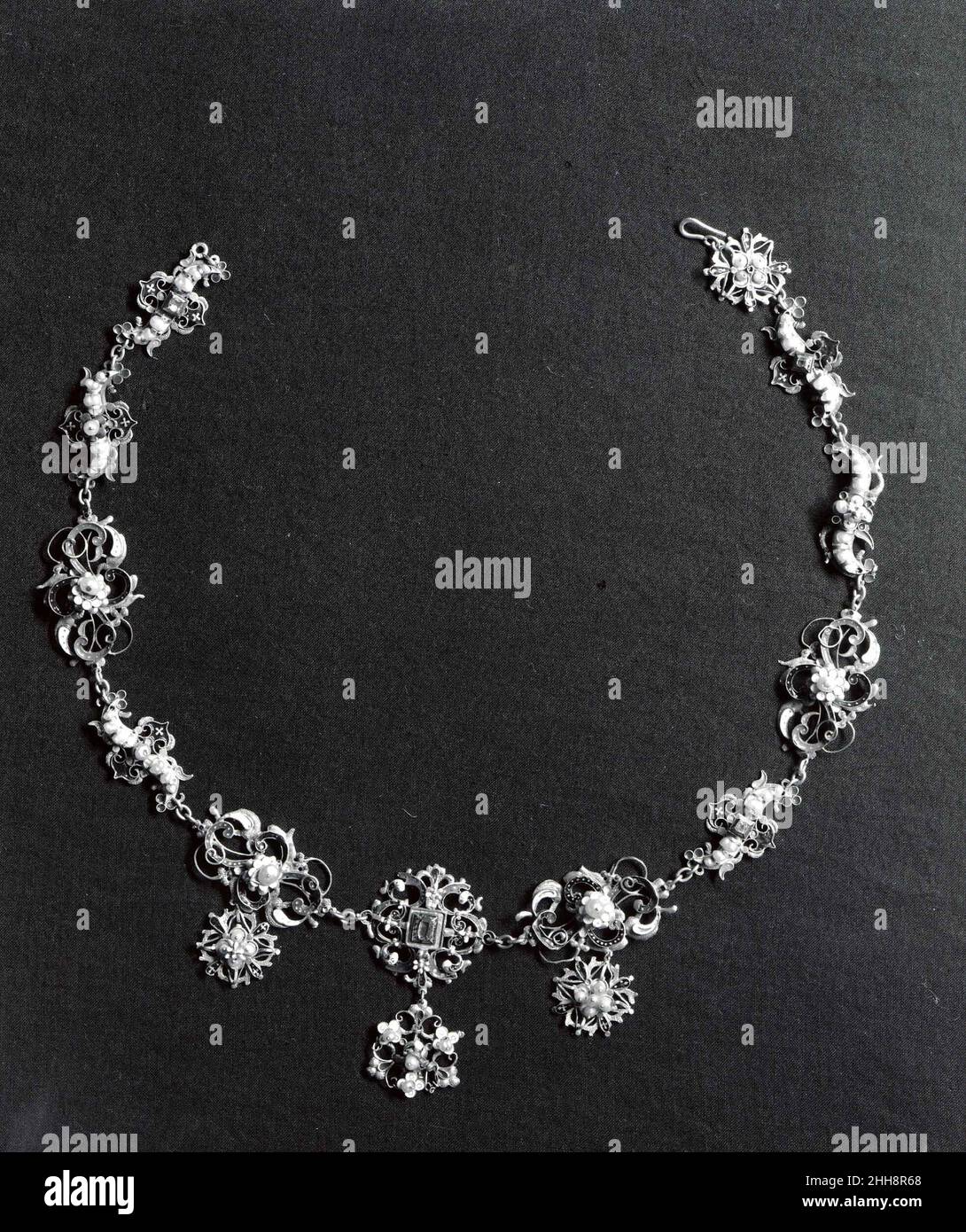 Halskette aus fünfzehn Kleiderornamenten um 1600 wahrscheinlich Siebenbürgisch, möglicherweise Süddeutschland Diese Halskette wurde, wahrscheinlich im 19. Jahrhundert, aus fünfzehn Kleiderornamenten aus dem frühen 17. Jahrhundert zusammengesetzt. Die Prävalenz dieser Ornamente, die als Boblar bezeichnet werden, in den Inventaren ungarischer Frauen des 16. Und 17. Jahrhunderts legt nahe, dass sie relativ preiswert waren, eine Theorie, die durch die minimale Verwendung von Edelmetall gestützt wird. Die Schmuckstücke wurden auf der Rückseite, vermutlich vom Hersteller, häufig mit Initialen markiert; im Falle des vorliegenden Werkes „GK“ und „HB“. Hals Stockfoto