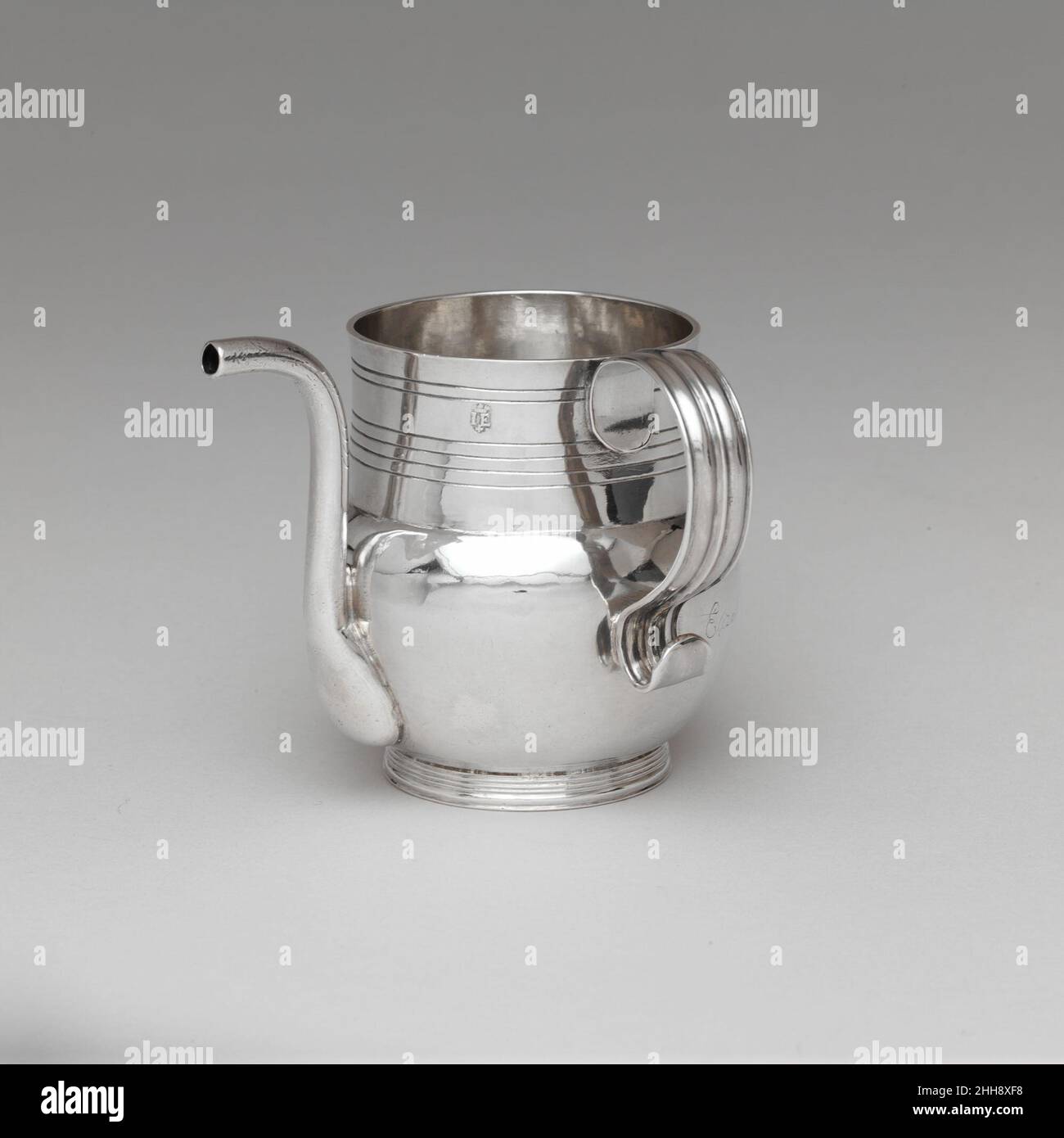 Spout Cup 1700–1725 John Edwards eine der spezialisierten Formen von Trinkgefäßen, die Ende des 17. Jahrhunderts in Amerika hergestellt wurden, war der Spout Cup. Der lange, schmale, scharf gekrümmte Auslauf ermöglichte es einem Kind oder bettlägerigen Erwachsenen, leichter aus der Tasse zu schlürfen, deren Griff rechtwinklig zum Auslauf angebracht war, um den Server zu unterstützen. An diesem Beispiel sind Zahnspuren am offenen Ende zu erkennen. Dieser Becher gehörte Elizabeth Greenleaf, die vermutlich die erste weibliche Apothekerin in Amerika war. Becher Mit Ausguss. Amerikanisch. 1700–1725. Silber. Hergestellt in Boston, Massachusetts, USA Stockfoto