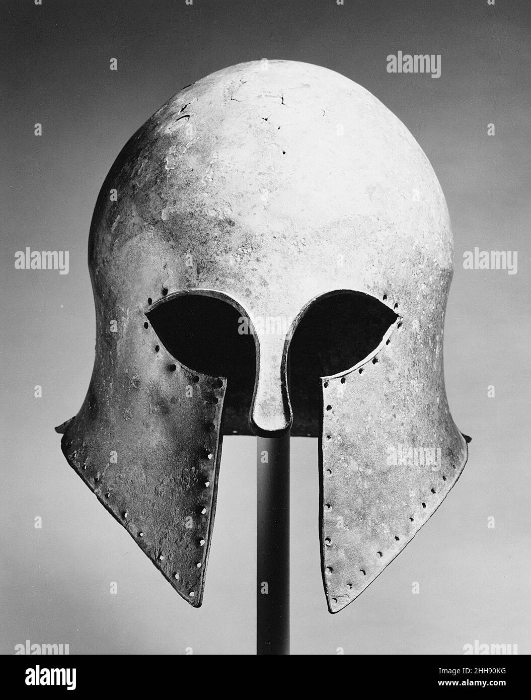 Bronzehelm des korinthischen Typs Ende des 6th. Jahrhunderts v. Chr. Griechisch der charakteristischste griechische Helm ist der des korinthischen Typs. Es zeichnet sich durch die Aussparungen für die Augen, das schmale Nasenstück und die kleine Öffnung für Lippen und Kinn aus. Die Löcher um die Kanten sind für die Befestigung einer Verkleidung. Es begann um 700 v. Chr. verwendet zu werden, und es gibt bedeutende Beweise, um seinen Ursprung in Korinth zu belegen. Diese Art von Helm entwickelte sich in Form und wurde mit großer Kunst ausgeführt.. Bronzehelm vom korinthischen Typ. Griechisch. Spätes 6th Jahrhundert B.C.. Bronze. Archaisch. Bronzen Stockfoto