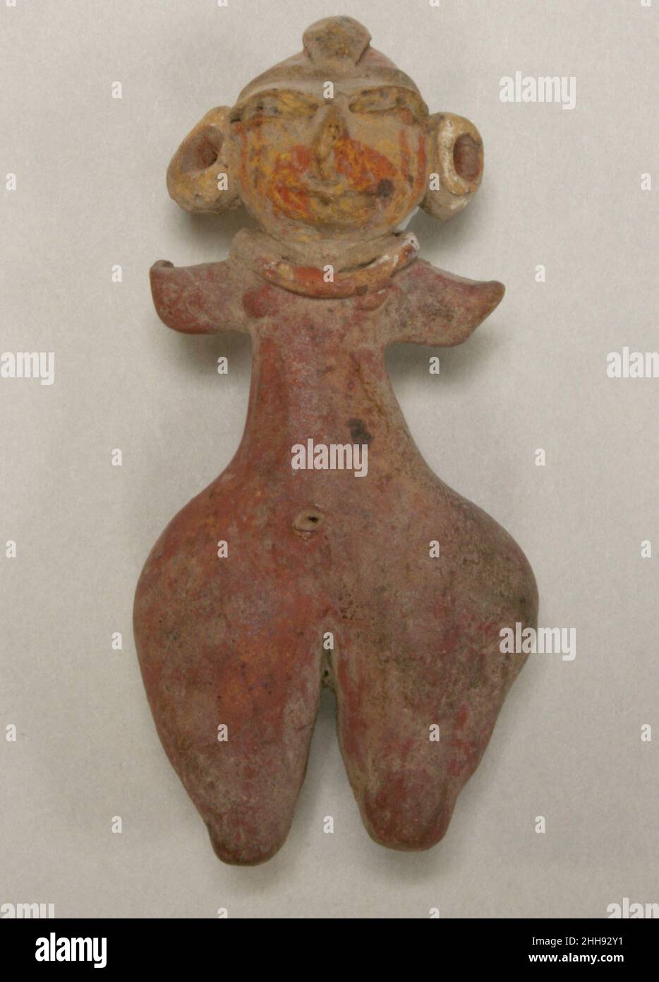 Weibliche Figur 10th. Jahrhundert v. Chr. Tlatilco Diese solide, handmodellierte Keramikfigur ist rötlich-hellbraun bis gelb und mit einem orange-roten Pigment bemalt. Die anatomische Genauigkeit wird nur wenig in den Blick genommen, da sie sich durch die gewölbten Hüften, die kleine Taille und die kleinen Arme auszeichnen. Eine Halskette passt sich den dicken Konturen des Halses an, und das zentrale Haarsträhnen erstreckt sich über den Hinterkopf. Keine der kleinen Perforationen in den übergroßen Ohren geht nach hinten. Diese Figur, die vor etwa drei Jahrtausenden im Tal von Mexiko geformt wurde, gehört zu einer Gruppe von Keramikfiguren, die gemeinsam als die bekannt sind Stockfoto