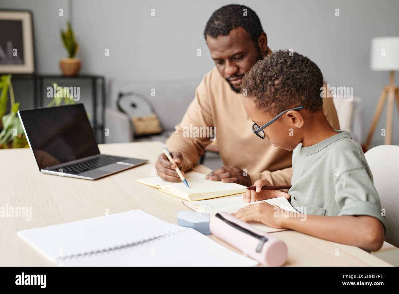 Porträt eines fürsorglichen Vaters, der dem Sohn bei den Hausaufgaben hilft, während er zu Hause studiert und Platz kopiert Stockfoto