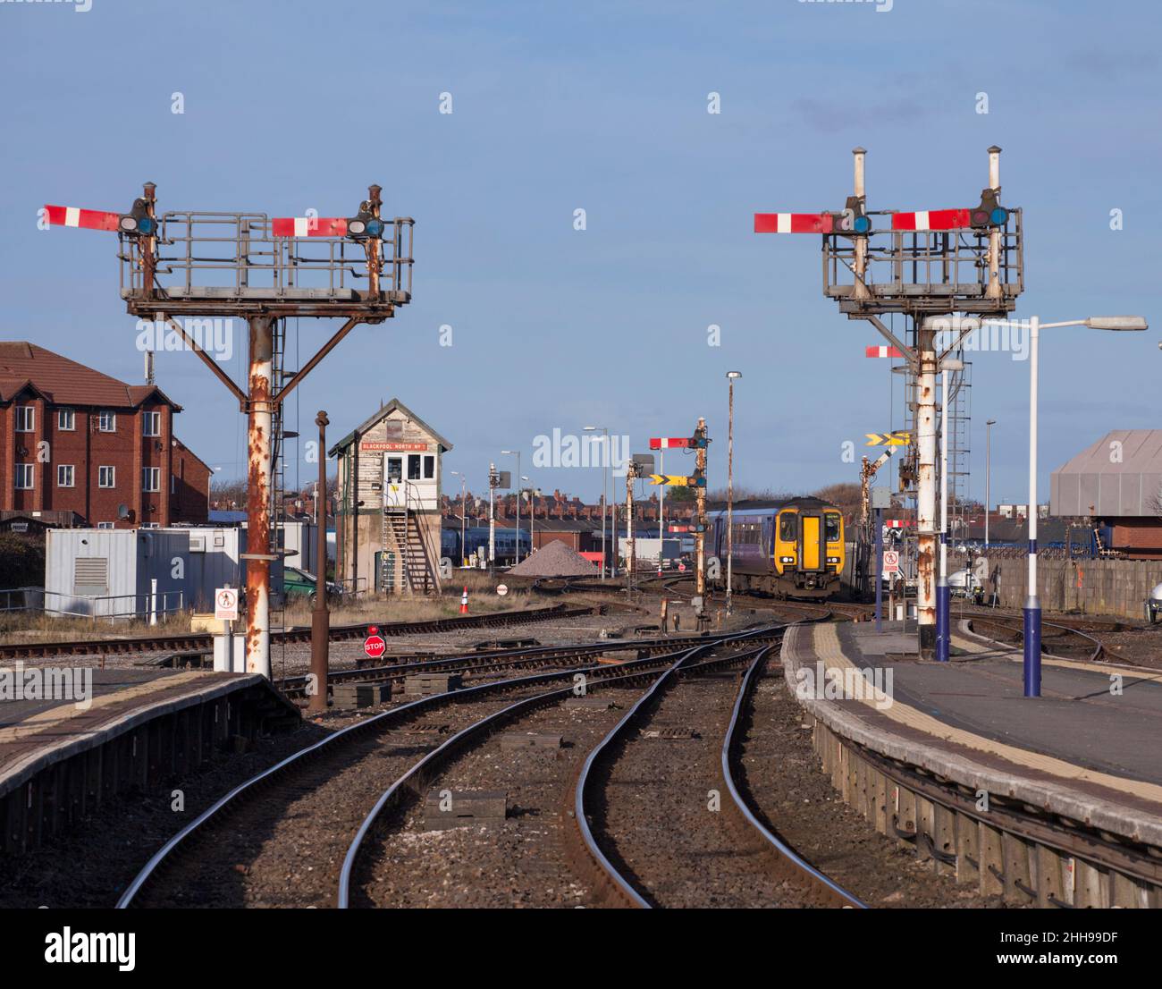 Der Sprinterzug Northern Rail der Klasse 156 kommt am Bahnhof Blackpool North mit den Signalen der mechanischen Semaphore-Halterung und der Signalbox an Stockfoto