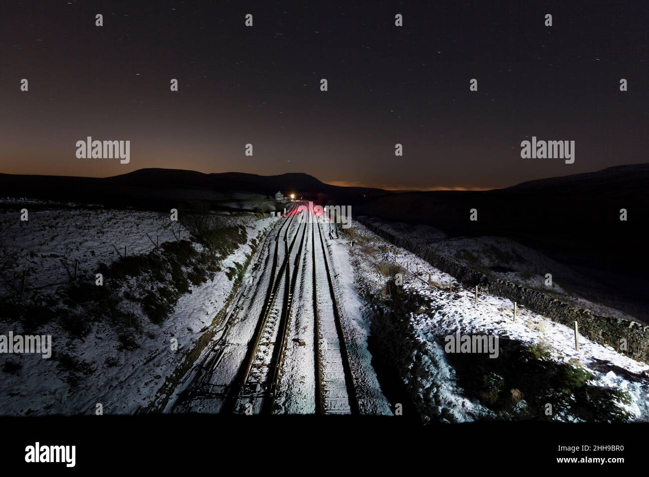 Schneebedeckte Strecke auf der Eisenbahnlinie Settle nach Carlisle in Blea Moor in einer dunklen Winternacht Stockfoto