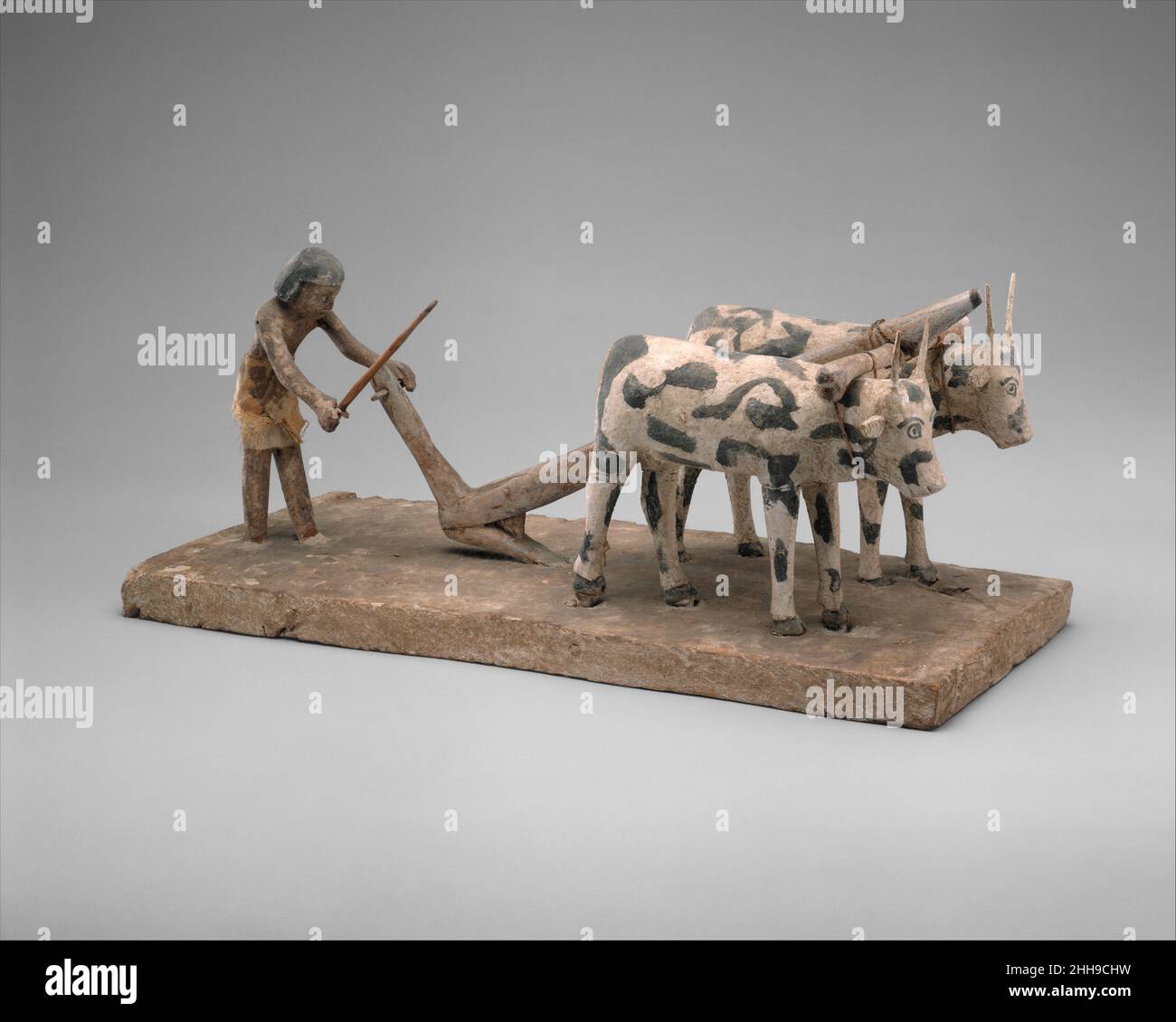 Modell eines Mannes, der pflügt, ca. 1981–1885 v. Chr. Mittleres Königreich der Bauer, Füße tief im Boden, stapft hinter dem hakenförmigen Pflug, der von zwei Ochsen gezogen wird. Die alten ägyptischen Pflüge waren aus Holz und hatten die Form eines Hakens. Es ist nicht möglich, den Boden mit solchen Pflügen zu drehen, sie dienen nur dazu, den Boden zu öffnen. Das ultimative Ziel dieser Art des Pflügens war es daher, die Samen gut in den Boden zu legen. Texte scheinen darauf hinzuweisen, dass ein Pflug zwar das Eigentum des Bauern gewesen sein mag, die Ochsen aber von staatlichen oder Tempeleinrichtungen verpachtet wurden. Die Ägypter glaubten, dass sie auch in der arbeiten mussten Stockfoto