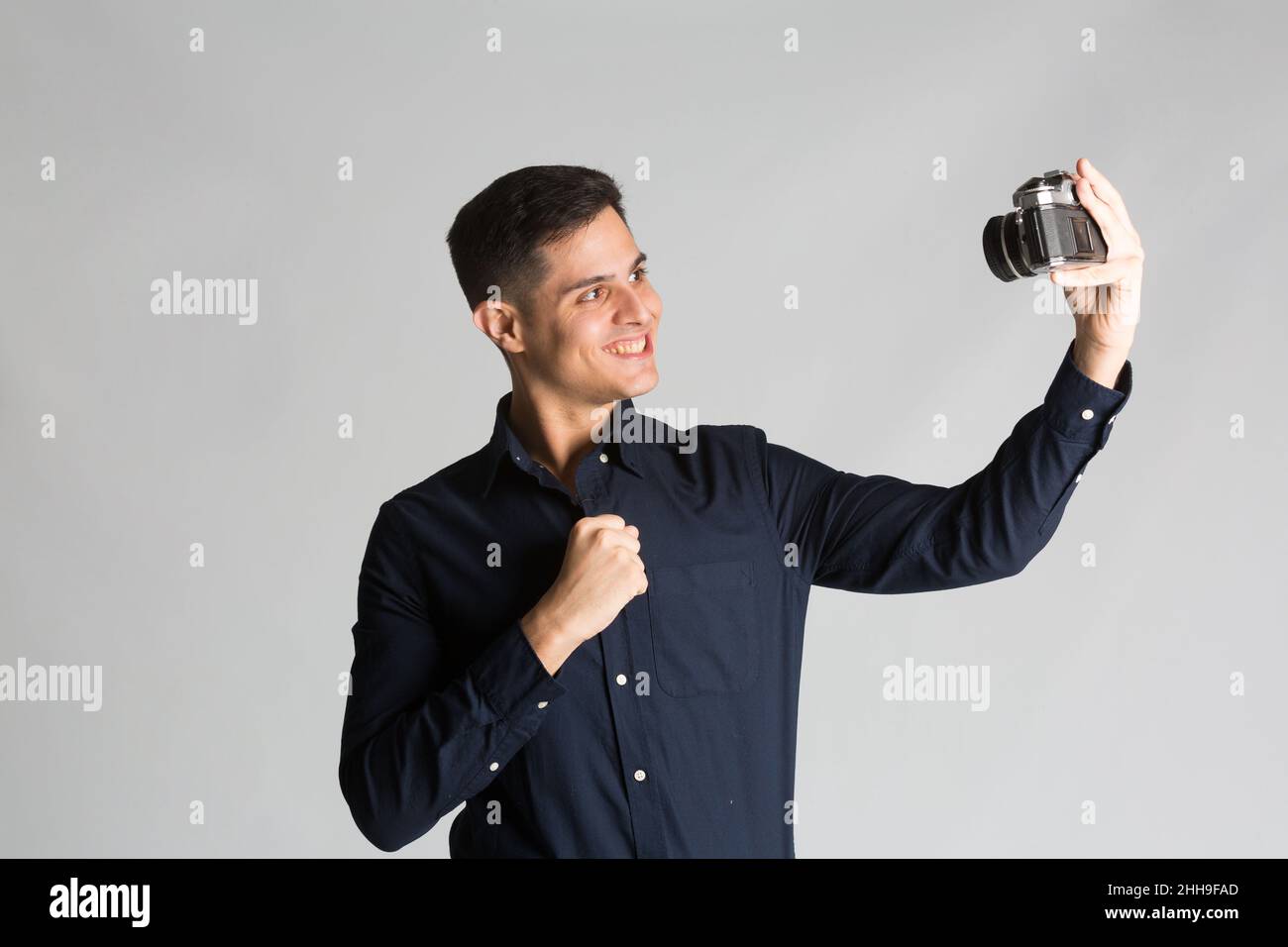 Selfie mit alter analoger Kamera auf Studiohintergrund Stockfoto