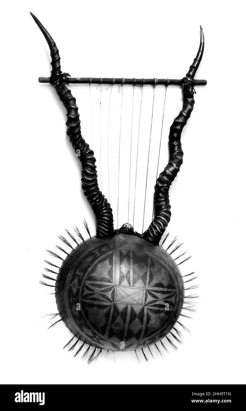 Bowl Lyre 19th Century Ugandan oder Kenyan Dekorative Leier für den Export, mit Kürbis-Körper und Antilopenhornarmen. Der Rand des Kürbisse ist mit Borsten verziert. Die Leier haben zwei Holz- oder Hornarme, die vom Körper aus projizieren und eine Querlatte tragen, an der die oberen Enden der Saiten befestigt sind. Die Saiten liegen fast parallel zum Klangtisch. Afrikanische Leier werden aus Holz, Kürbissen, Schildkröten oder Kokosnussschalen hergestellt. Die meisten afrikanischen Lyren haben keine Brücken; die Saiten schwingen gegen den Klangtisch, um einen summenden Klang zu erzeugen. Bowl Lyre 501927 Stockfoto