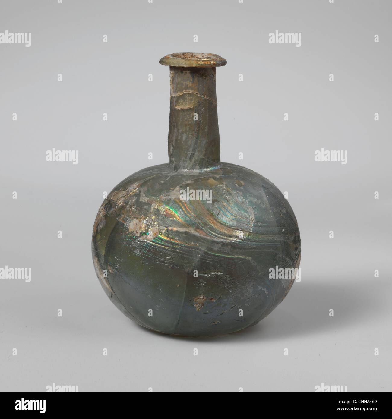 Parfümflasche aus Glas 2nd. Jahrhundert n. Chr. Roman Durchscheinend blassblaugrün.Rand ausgeklappt, nach unten, über und in; zylindrischer Hals, Leicht nach unten ausdehnend und an der Basis eingehäkelt; Kugelkörper; leicht konvierter Boden. Dickes, schweres Glas. Um den Körper herum gebrochen und repariert; Risse anspannen; starke Verwitterung und Lochfraß; brillante Irideszenz.. Parfümflasche aus Glas. Roman. 2nd Jahrhundert n. Chr.. Glas; geblasen. Mittelbritisch. Glas Stockfoto