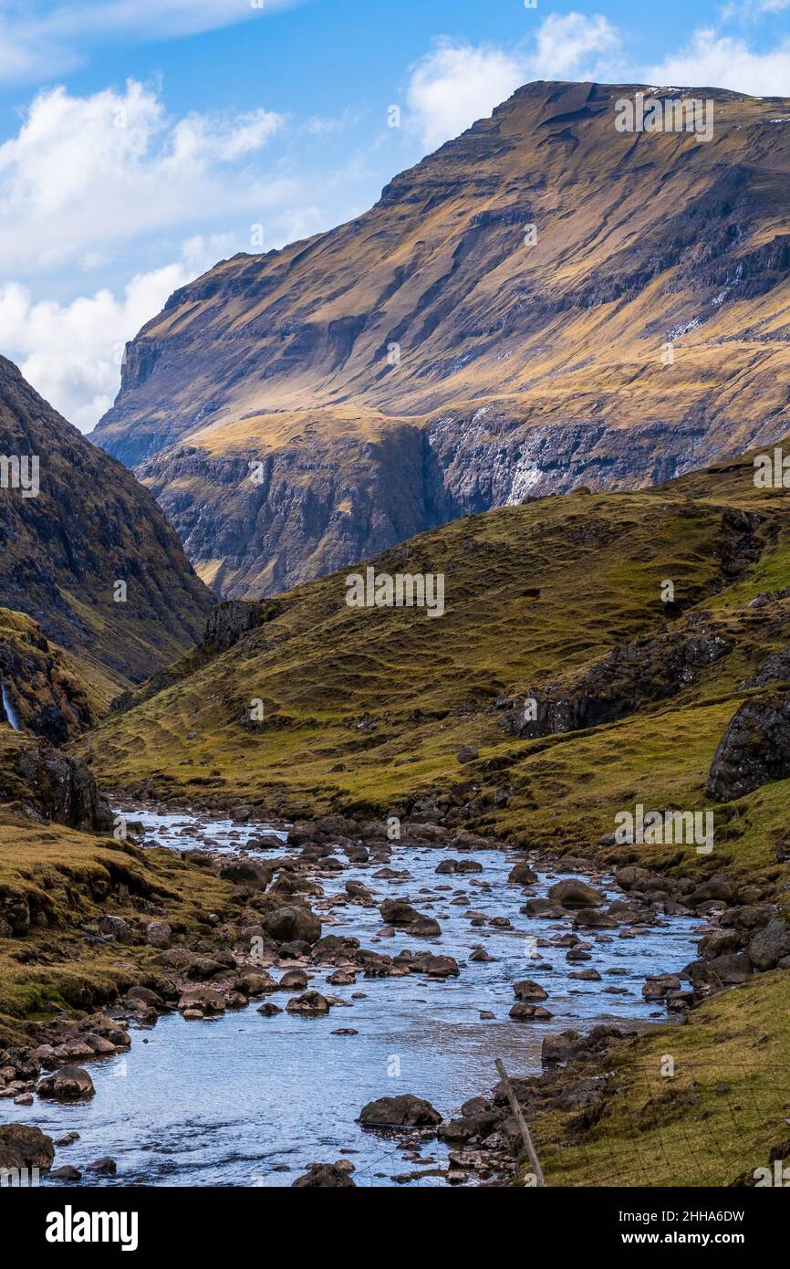 Ein felsiger, malerischer Fluss in Saksun, Färöer Inseln mit einem steilen Berg im Hintergrund. Stockfoto