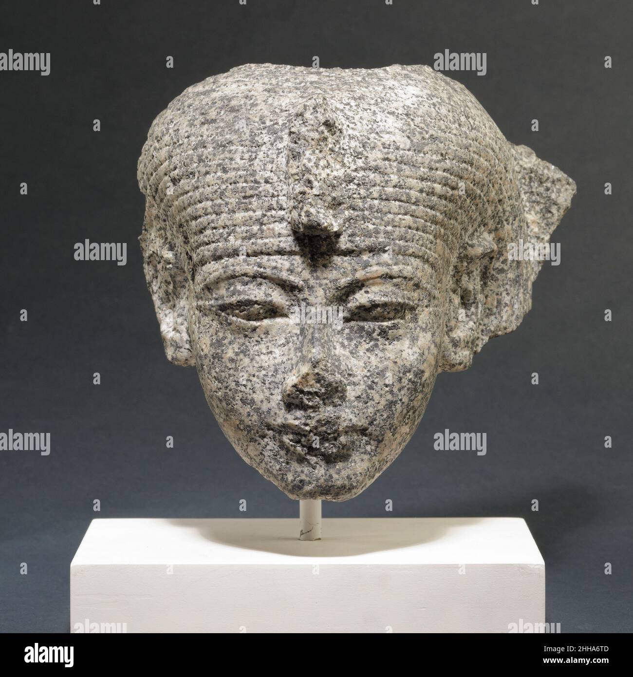 Kopf einer Göttin (?) Ca. 1336–1295 v. Chr. Neues Königreich, Post-Amarna-Zeit dieser Kopf stellt sicherlich eine Göttin dar, da sie die traditionelle einfache Dreierperücke trägt. Eine Krone oder ein Element saßen auf ihrem Kopf, und eine Steinension rechts vom Kopf deutet darauf hin, dass sie Teil einer Gruppe war, vielleicht neben einem männlichen gott oder alternativ auf der einen Seite eines Königs mit einem männlichen gott auf der anderen. Die Augen sind auffallend schmal. Ein Datum zur Herrschaft der post-Amarna Könige Aya oder Haremhab scheint sehr wahrscheinlich. Kopf einer Göttin (?). Ca. 1336–1295 V. CHR. Granodiorit (?). Neues Königreich, nach Amarna Peri Stockfoto