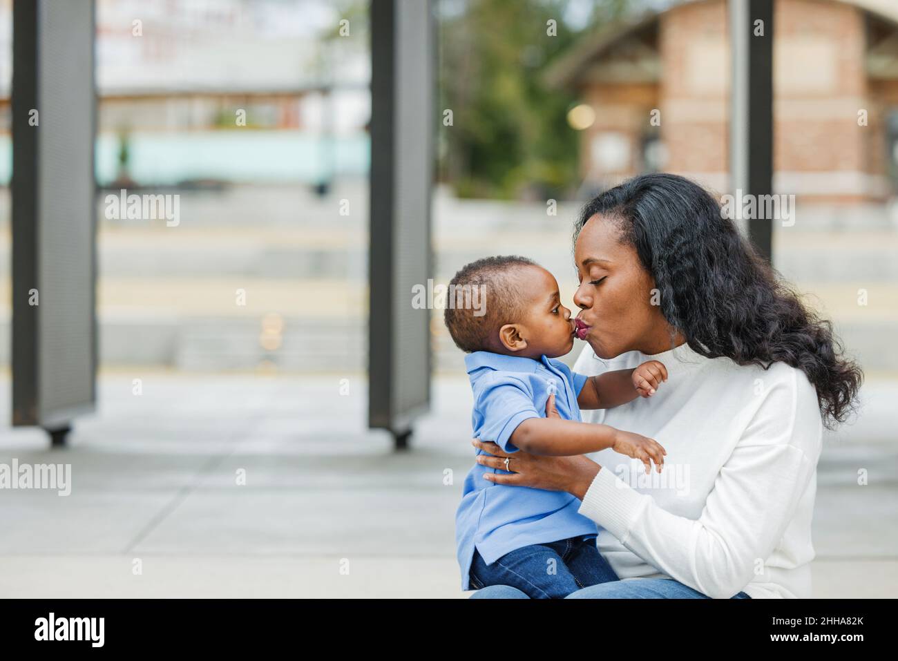 Eine schöne afroamerikanische Mutter, die ihrem Kleinkind einen Kuss gab Stockfoto
