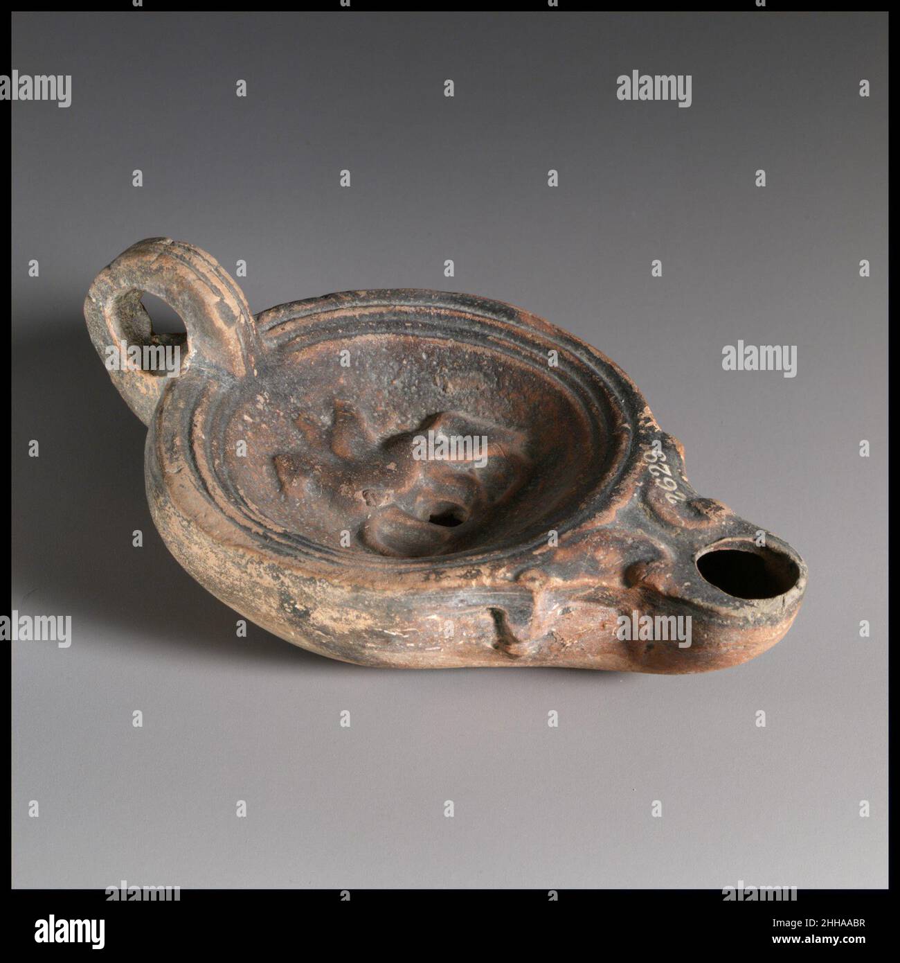 Terrakotta-Öllampe 1st Jahrhundert A.D. Roman Loeschcke Typ 4. Formgefertigte, mit Ringgriff. Discus: Geflügelter Pegasus, stehend, nach links, am Boden; ein einzelnes Füllloch in der Mitte zwischen Pegasus Beinen; mit einem Band aus Linien und Rillen um den Rand. Voluten flankierende Düse, mit großem Dochtloch. Zwei parallel eingeschnittene Linien schmücken die Oberkante des Griffs. Eingeprägte Ringbasis, und eine flache konkave Basis, mit einem dicken linearen Eindruck in der Mitte.. Terrakotta-Öllampe. Roman. 1st Jahrhundert n. Chr.. Terrakotta; Schimmel. Frühkaiserlich. Terrakotta Stockfoto