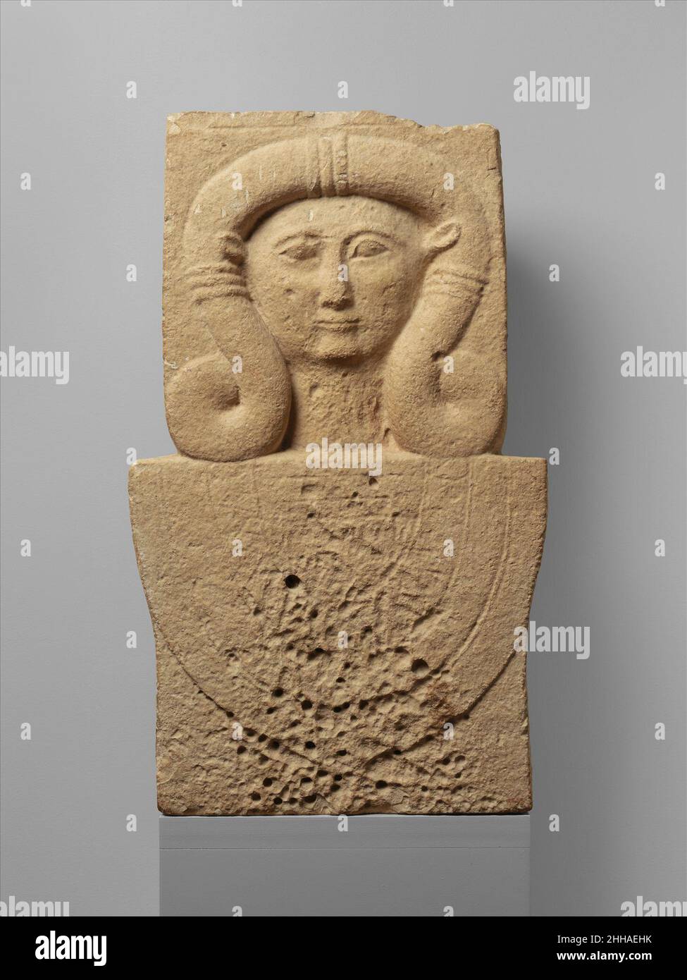 Kalksteinstele (Schacht) mit dem Kopf von Hathor 2nd Viertel des 6th Jahrhunderts B.C. Zypern der untere Teil des Schachtes wurde abgeschnitten; zwei Dübellöcher auf der oberen Oberfläche erlaubten es, ein zusätzliches Element zu befestigen. Steinschäfte, die den Kopf der ägyptischen Göttin Hathor enthalten, kommen besonders häufig bei Amathus vor. Ihr Aussehen kann mit dem Aufkommen der ägyptischen Herrschaft über die Insel verbunden werden. Sie spielten eine Rolle im Kult der Großen Göttin Zyperns, die wie Hathor Schutz vor Tod und Schaden gewährte. Die Schächte treten auch in funerären Kontexten auf. Kalksteinstele (Sha Stockfoto
