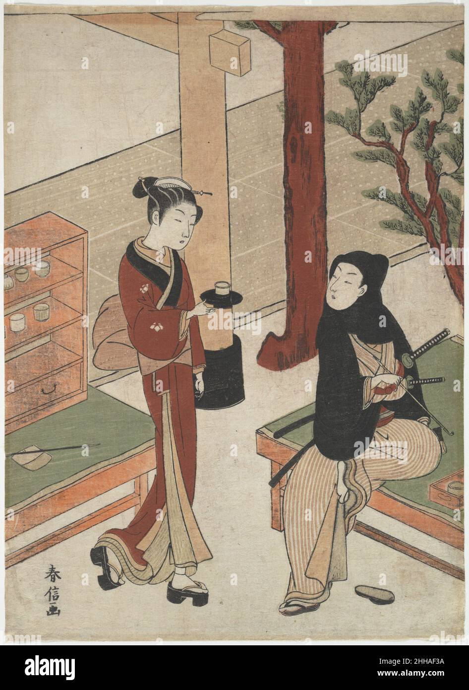 Osen wartet auf einen jungen Samurai Ca. 1770 Suzuki Harunobu Japanese das Familienwappen der Paulownia auf ihrem Kimono und das teilweise sichtbare Torii-Tor kennzeichnen das Thema dieses Abdrucks als Osen, anmutige Kellnerin des Kagiya-Teehauses am Eingang zum Kasamori-Inari-Schrein. Ein junger Samurai, zwei Schwerter an der Hüfte, sitzt entspannt auf einer Bank und dreht sein Gesicht, um Osen anzugucken, der sich nähert, um ihm Tee zu servieren. Das schöne Osen und der gutaussehende Gallant sind das Bild von stilvollen Edoiten aus der Mitte des achtzehnten Jahrhunderts. Osen Waiting on a Young Samurai 40991 Stockfoto