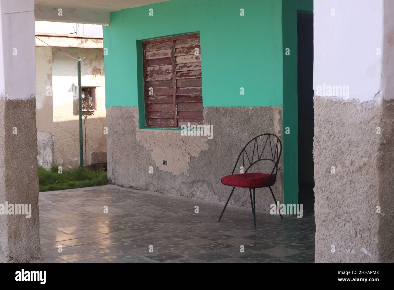 Leerer Sitzplatz am Eingang eines heruntergekommenen Hauses in Havanna, in der Nähe des Ozeans. Wartekonzept. Mangel an Illusion Konzept. Stockfoto