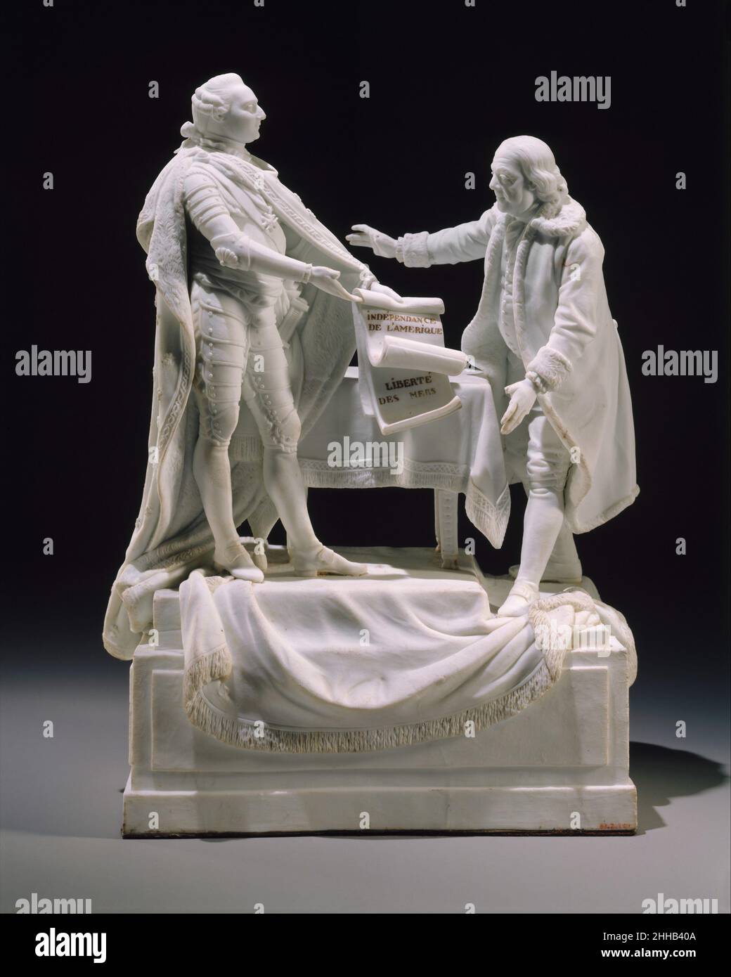 Figur von Louis XVI und Benjamin Franklin 1780–85 Charles-Gabriel Sauvage, genannt Lemire pere Diese Figurengruppe aus unglasiertem Porzellan zeigt den französischen König Louis XVI. Und den amerikanischen Staatsmann Benjamin Franklin zum Gedenken an die Unterzeichnung zweier Verträge zwischen Frankreich und den Vereinigten Staaten im Jahr 1778. Mit den Inschriften „INDEPENDENCE DE L'AMERIQUE“ und „LIBERTE DES MERS“ feiert das Porzellan die Verträge zur Anerkennung der amerikanischen Unabhängigkeit und zur Gewährleistung des Rechts auf Handel zwischen den beiden Nationen ohne britische Einmischung. Louis ist in zeremoniellem Kleid dargestellt, und Franklin in schlichtem Gewand zeigt die Stockfoto Figur von Louis XVI und Benjamin Franklin 1780–85 Charles-Gabriel Sauvage, genannt Lemire pere Diese Figurengruppe aus unglasiertem Porzellan zeigt den französischen König Louis XVI. Und den amerikanischen Staatsmann Benjamin Franklin zum Gedenken an die Unterzeichnung zweier Verträge zwischen Frankreich und den Vereinigten Staaten im Jahr 1778. Mit den Inschriften „INDEPENDENCE DE L'AMERIQUE“ und „LIBERTE DES MERS“ feiert das Porzellan die Verträge zur Anerkennung der amerikanischen Unabhängigkeit und zur Gewährleistung des Rechts auf Handel zwischen den beiden Nationen ohne britische Einmischung. Louis ist in zeremoniellem Kleid dargestellt, und Franklin in schlichtem Gewand zeigt die Stockfoto