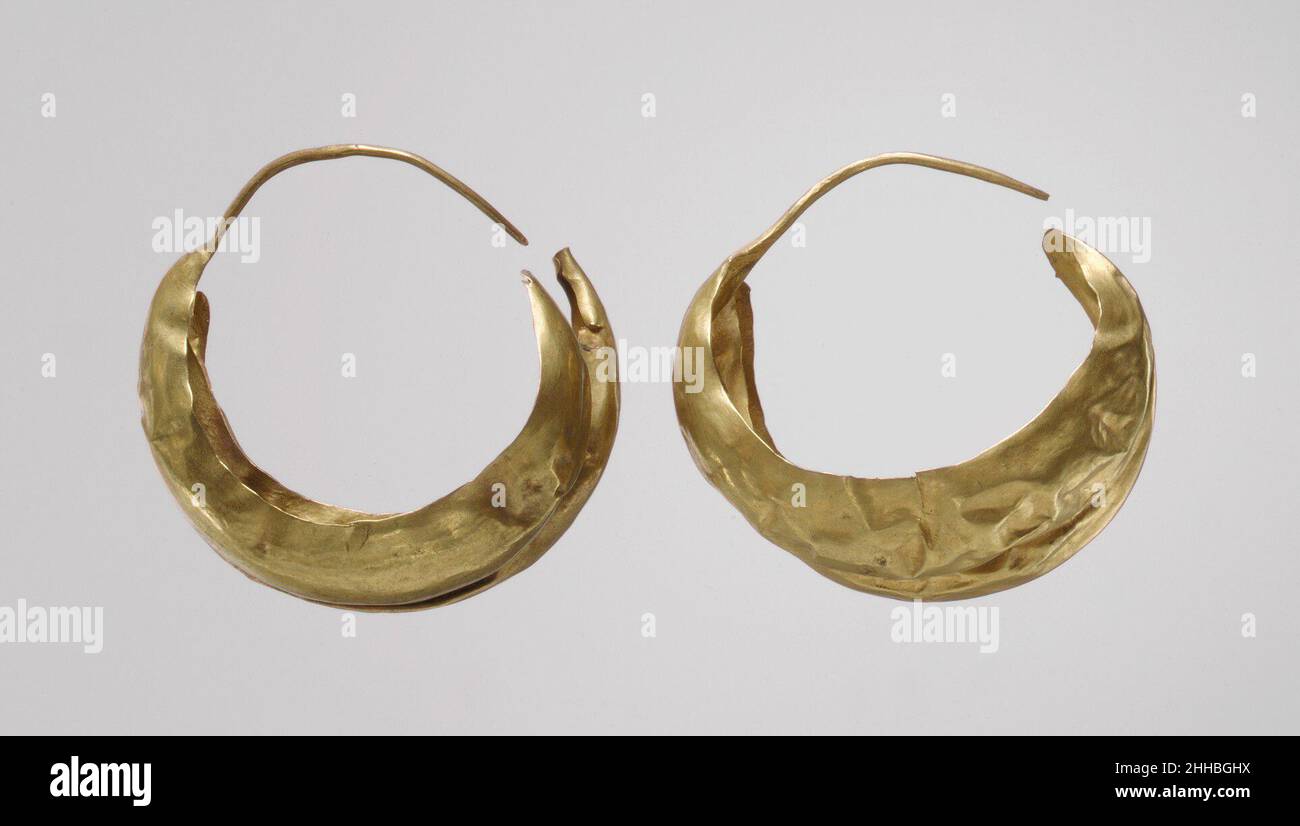 Ohrring ca. 2600–2500 v. Chr. Sumerian Diese Ohrringe (MMA 33.35.45 und MMA 33.35.46) stammen aus der sogenannten Großen Todesfalle, die wahrscheinlich Teil eines königlichen Grabes mit einer fast vollständig zerstörten Steinkammer war. In der Grube wurden die Leichen von sechs bewaffneten Männern und achtundsechzig Personen, die als Frauen oder junge Mädchen gedacht wurden, angelegt, alle mit dem schönsten Schmuck aus Gold, Lapislazuli und Karneol geschmückt.die Ohrringe sind typisch für die aus den königlichen Gräbern. Aus zwei Goldblechen gefertigt, ist jedes wie eine hohle Sichel oder ein offenes Boot mit erhöhten Enden geformt. Die Halbmonde waren überformt Stockfoto
