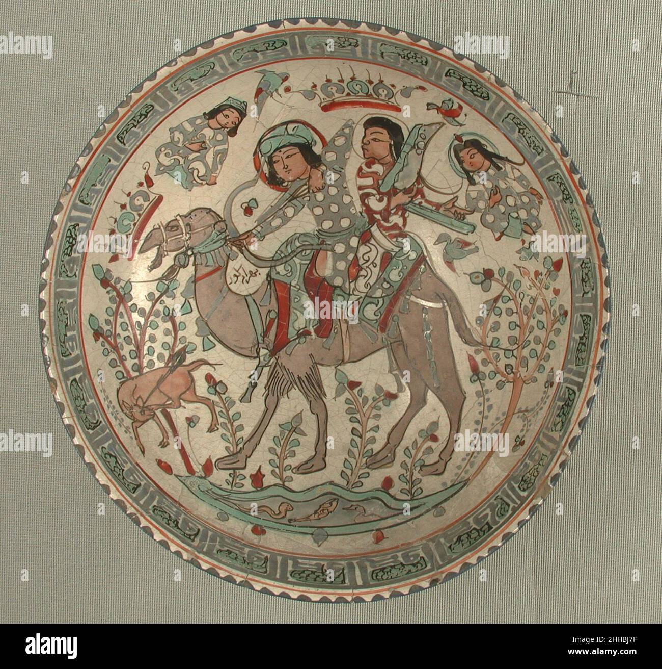 Bowl 12th–13th Century der sasanische Held Bahram Gur, eine der buntesten Figuren der persischen Epos-Literatur, ist auf dieser Schale abgebildet, die mit einem seiner Sklaven, Azadeh, auf einem Kamel reitet und hier Harfe spielt. Um seine Jagdkünste auf die Probe zu stellen, bat Azadeh Bahram Gur, das Bein und das Ohr der Gazelle mit seinem Pfeil in einem Schlag zu durchbohren. Schüssel 451389 Stockfoto