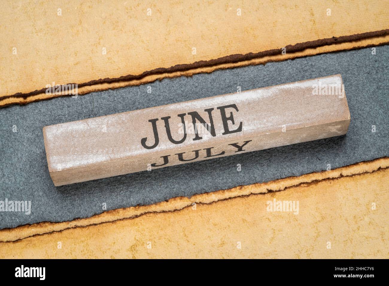 Juni Text auf grunge Holzblock gegen handgefertigtes Lapppapier in Blau- und Gelbtönen, Kalenderkonzept Stockfoto