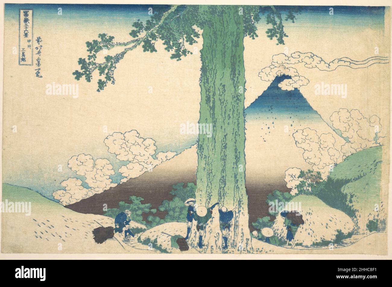 Mishima Pass in der Provinz Kai (Kōshū Mishima goe), aus der Serie sechsunddreißig Ansichten des Fuji-Berges (Fugaku sanjūrokkei ca. 1830–32 Katsushika Hokusai der japanische Mishima-Pass liegt in einer bergigen Gegend nördlich des Fuji-Berges, nahe der Grenze der ehemaligen Provinzen Kai und Suruga. Eine hoch aufragende Zypresse wird von Reisenden umarmt, die ihre Überschwänglichkeit und ihren Triumph beim Erreichen des alten Baumes zum Ausdruck bringen. Selbst der Berg Fuji in der Ferne wird vom monumentalen Baum in den Schatten gestellt. Der Kontrast zwischen den kleinen menschlichen Figuren und den riesigen natürlichen Formen offenbart Hokusais Empathie mit den Reisenden. Mishima Pass in Kai P Stockfoto
