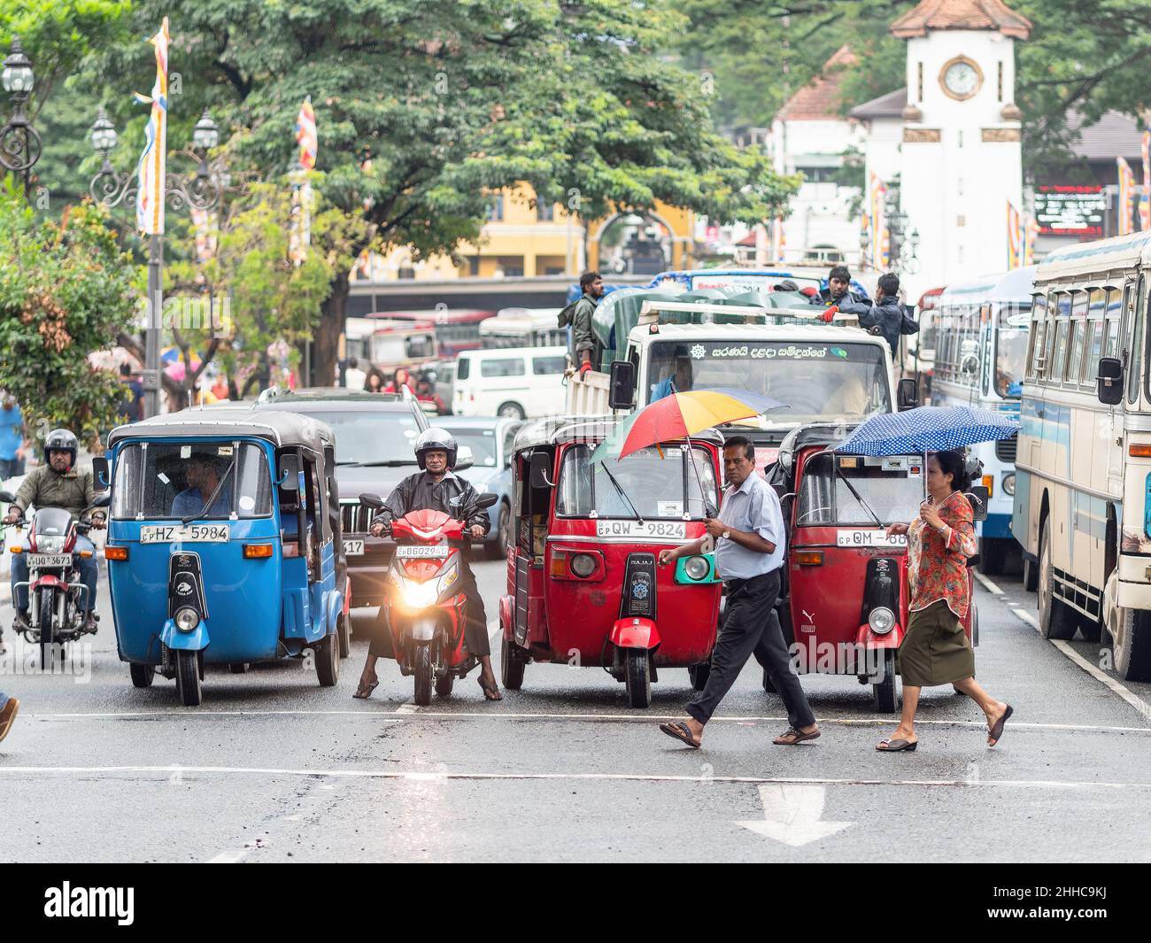 Fahrzeug wartet an einer Ampel, während Fußgänger an einem regnerischen Tag in Kandy in Sri Lanka die Straße überqueren. Stockfoto