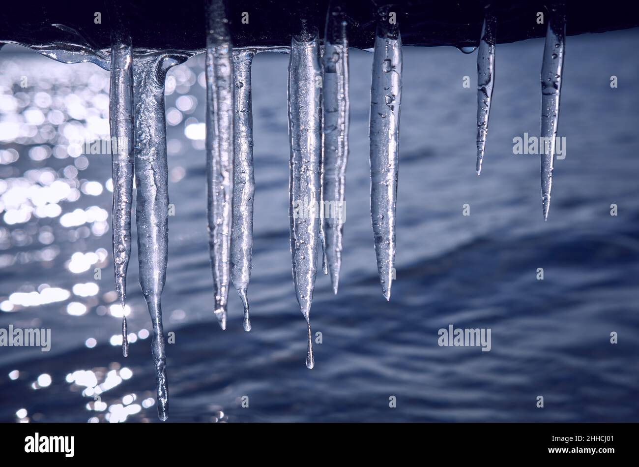 Eiszapfen hängen über dem Wasser. Stockfoto