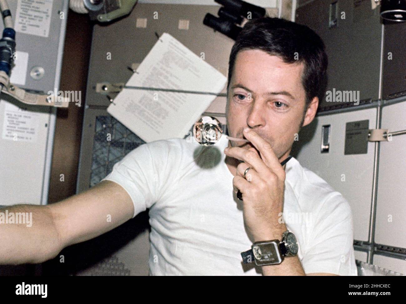 (1. Juni 1973) --- Wissenschaftler-Astronaut Joseph P. Kerwin, Wissenschaftspilot Skylab 2, bildet eine perfekte Kugel, indem er Wassertröpfchen aus einem Stroh in der Schwerelosigkeit bläst. Er ist im Crew-Quartier des Skylab Orbital Workshops Stockfoto